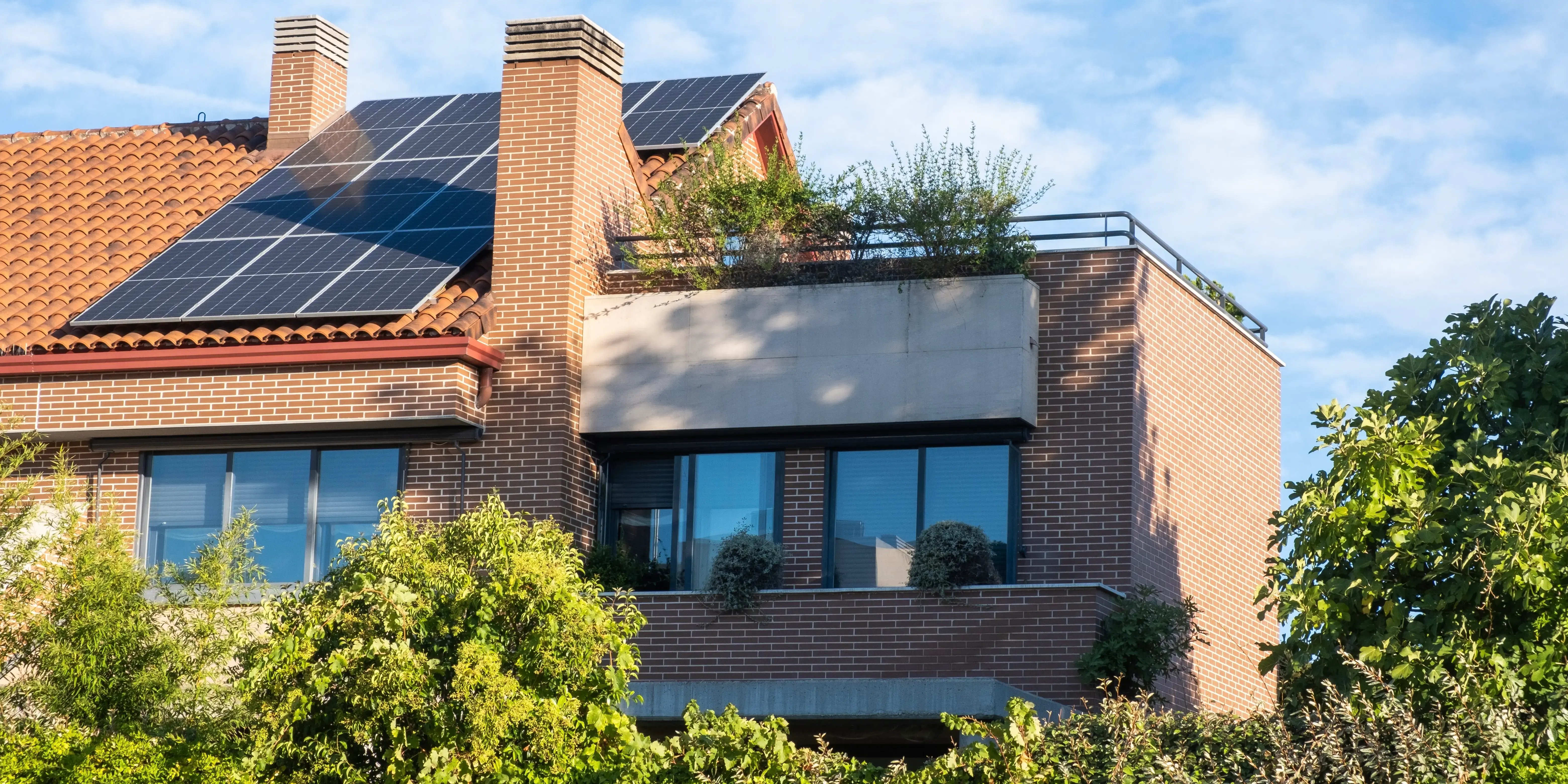 Casa rodeada de árboles y con páneles solares en el techo, tipo de casa moderna