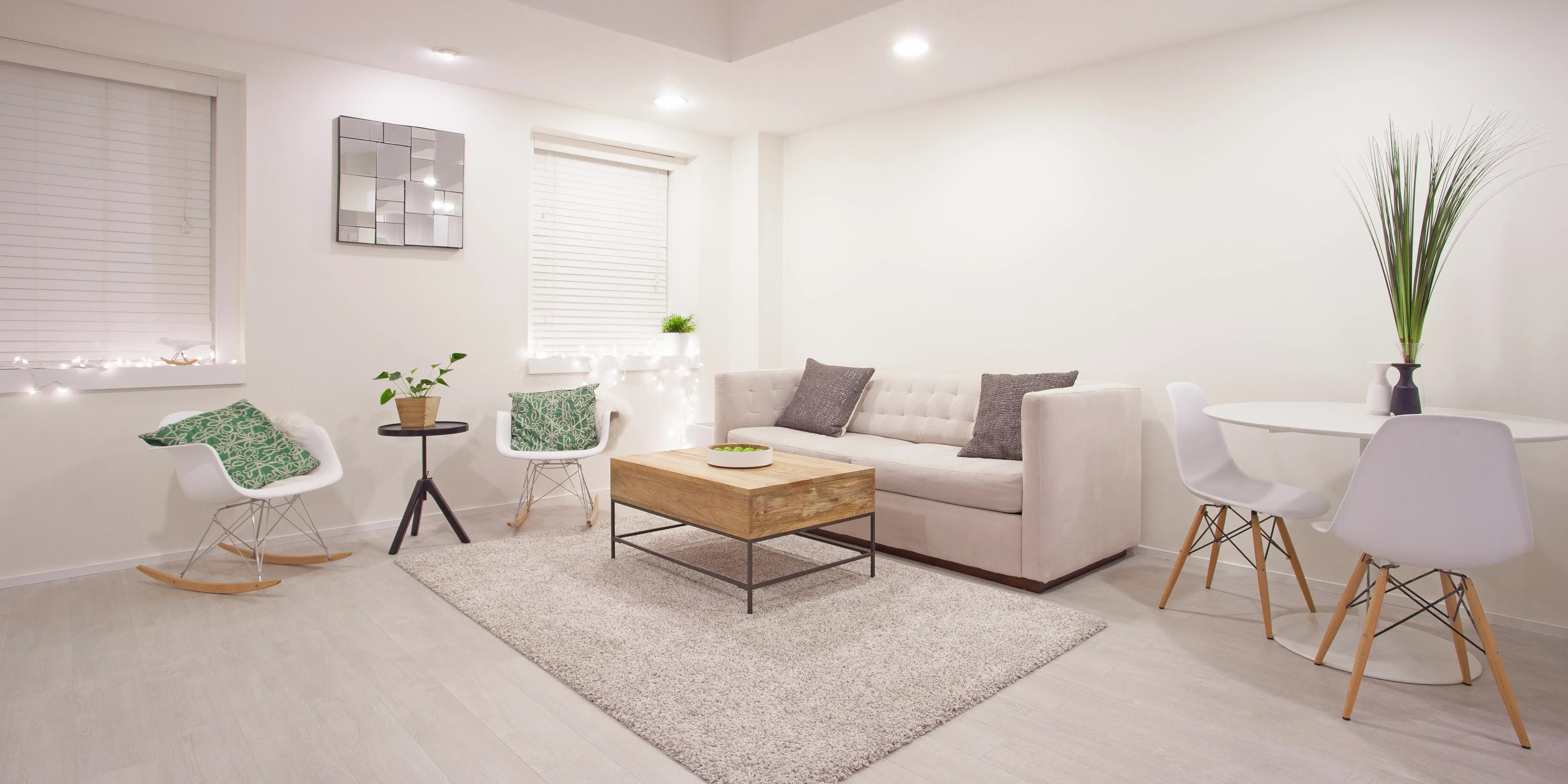Decoración de una sala estilo minimalista, con colores blanco, gris y beige, toques de madera y un espejo que amplía la vista