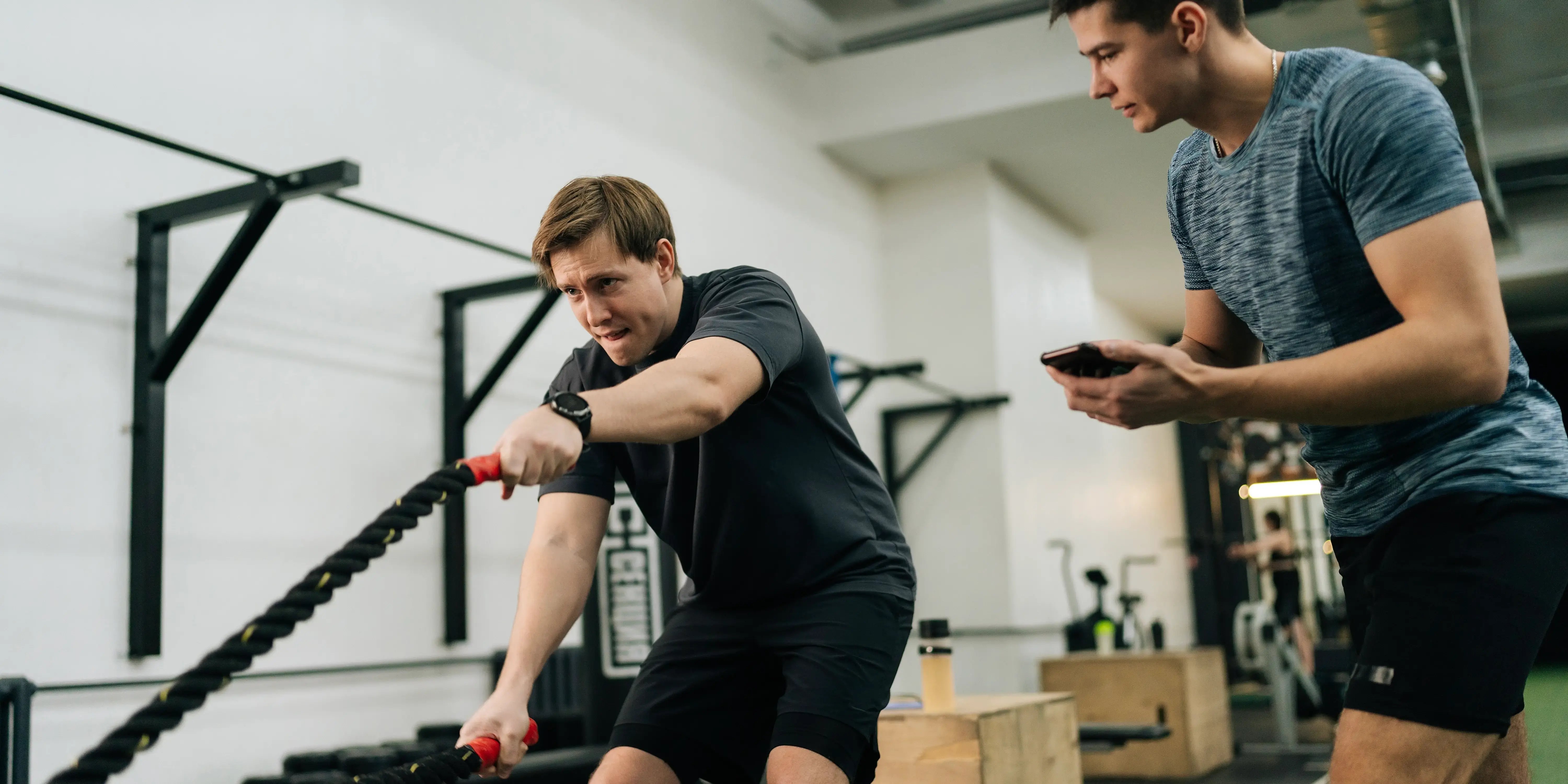 Entrenador personal entrenando al deportista principiante para realizar ejercicios de cuerdas de crossfit en gym de Bosque Real