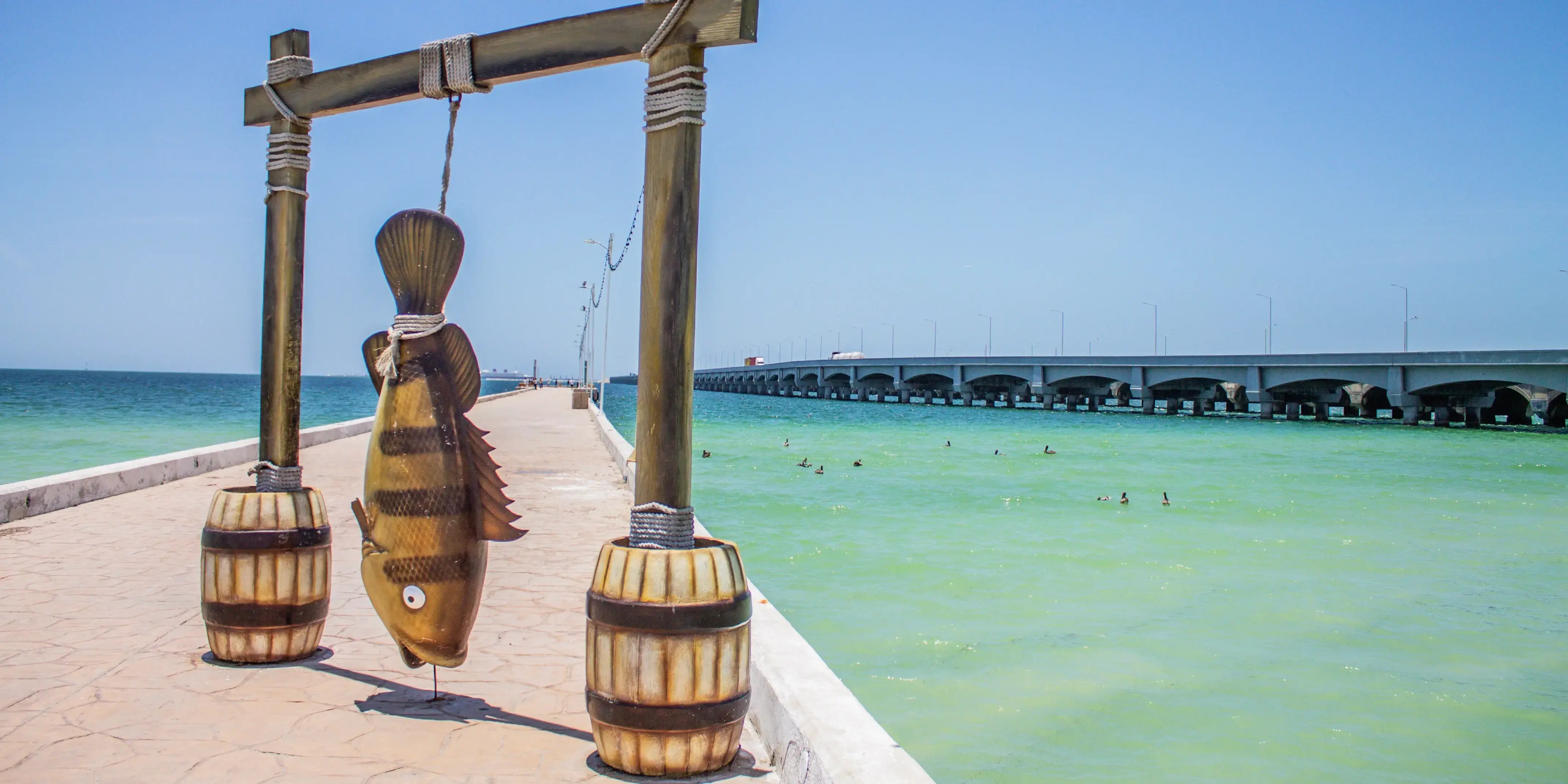 Estatua de pescado y vista del muelle. Puerto Progreso, cerca de Cabo Norte, Mérida