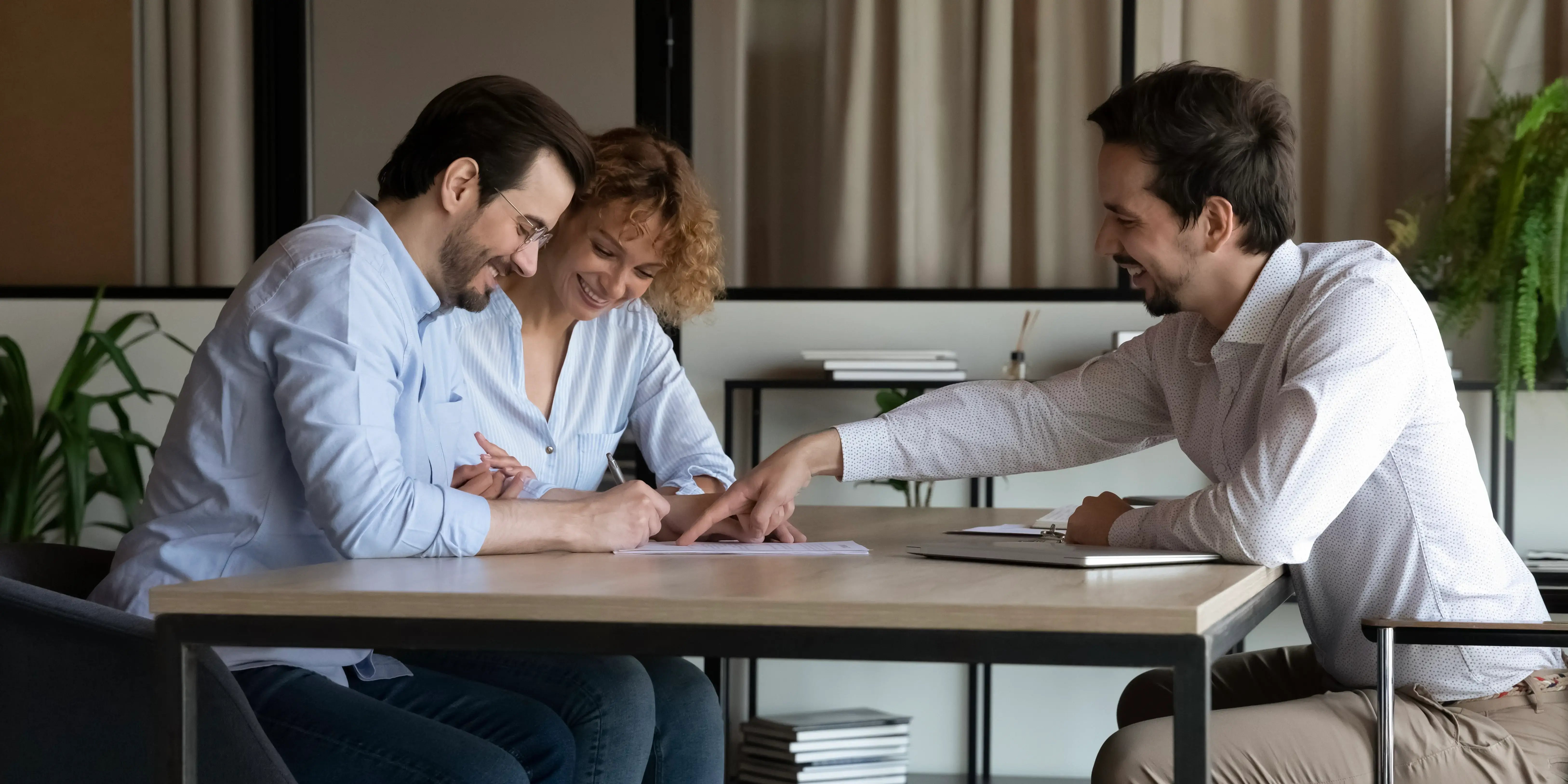 Experto hipotecario evaluando junto con una pareja la capacidad de pago para invertir en bienes raíces en México