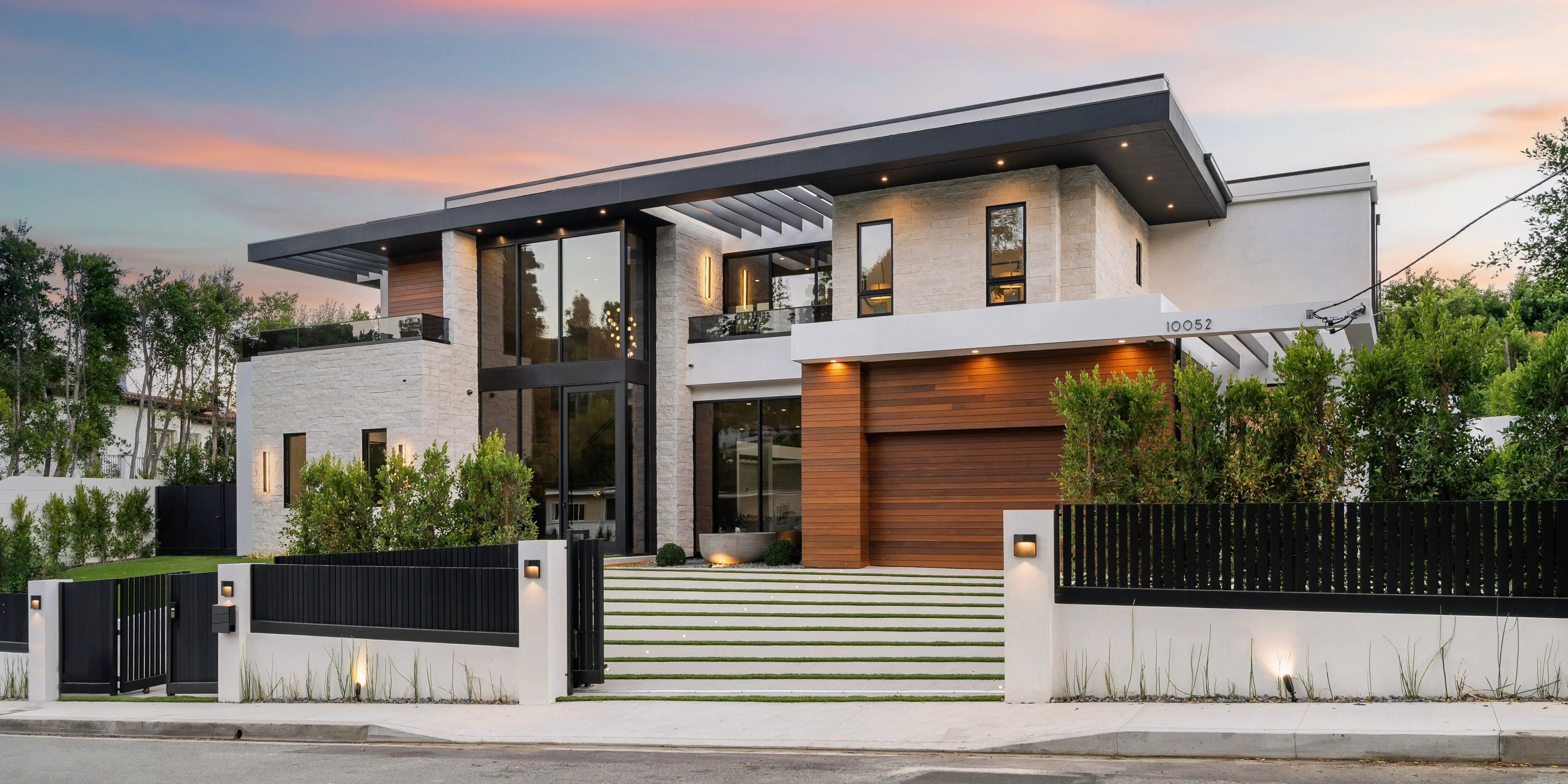 Fachada de casa contemporanea, blanca, con jardin frontal, iluminación cálida