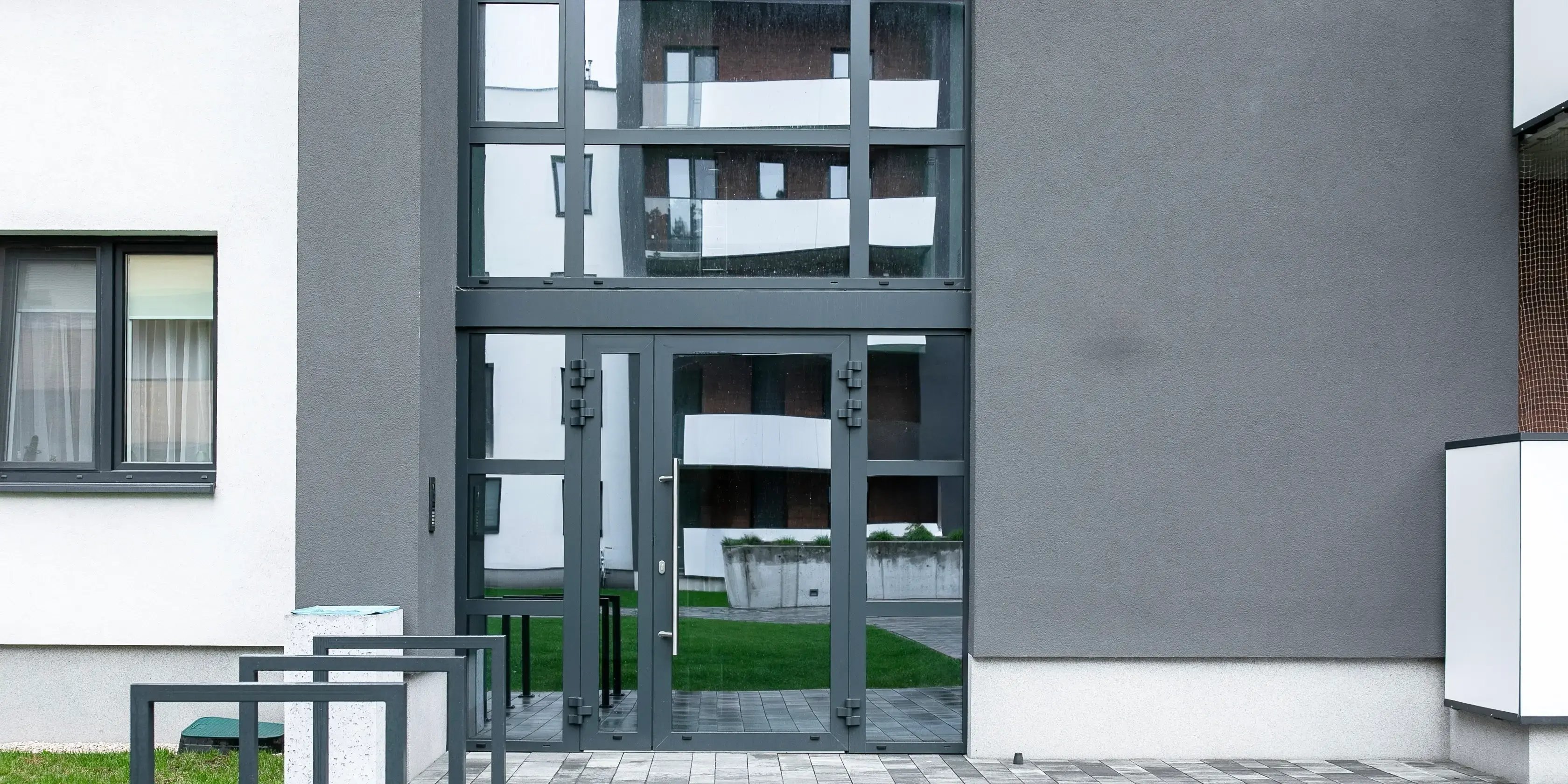Fachada moderna de un edificio con paredes grises y puertas negras con vidrio
