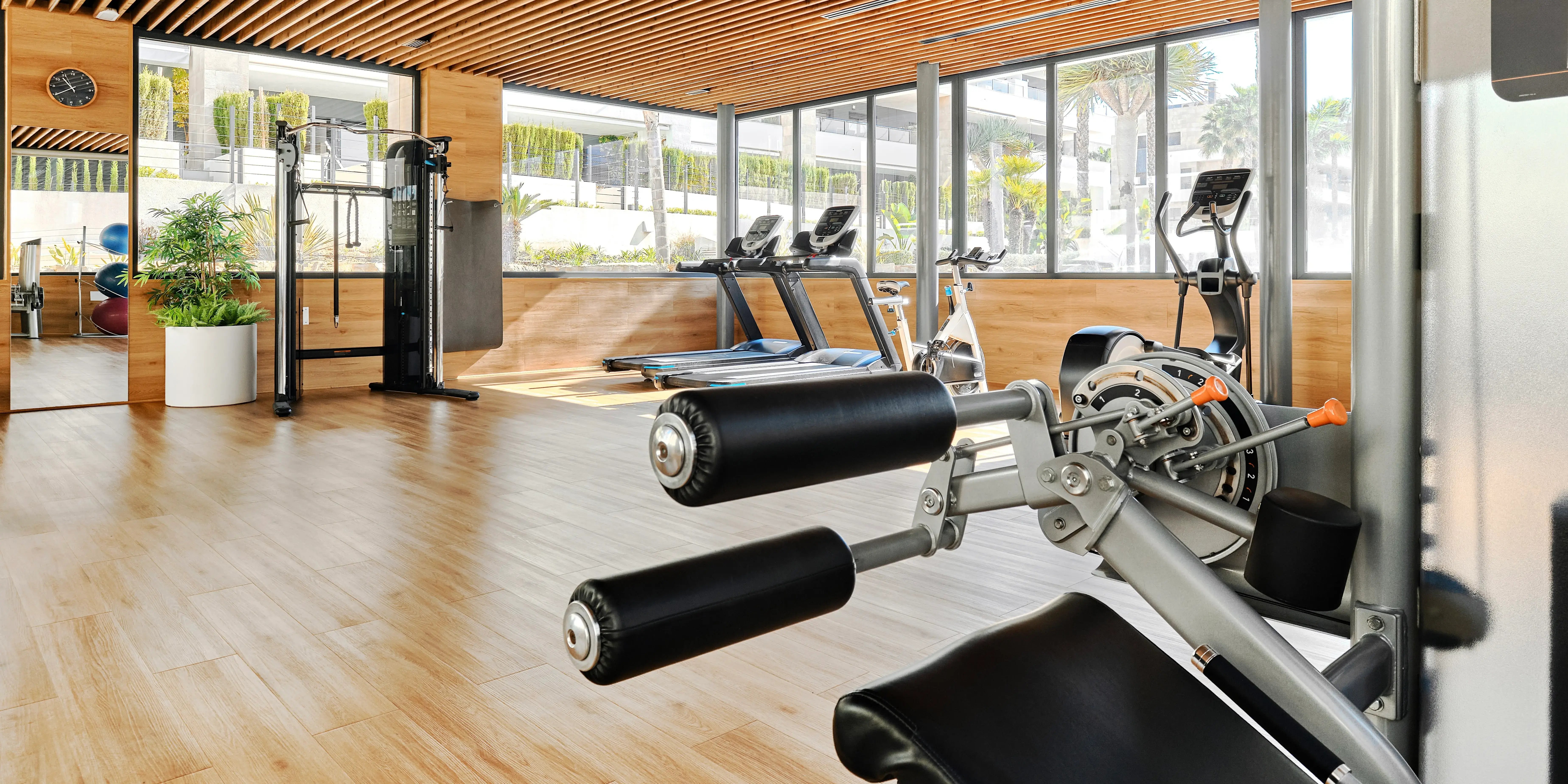 Gimnasio de un desarrollo inmobiliario con variedad de máquinas de entrenamiento, incluyendo cintas de correr, entrenadores elípticos, máquinas de pesas