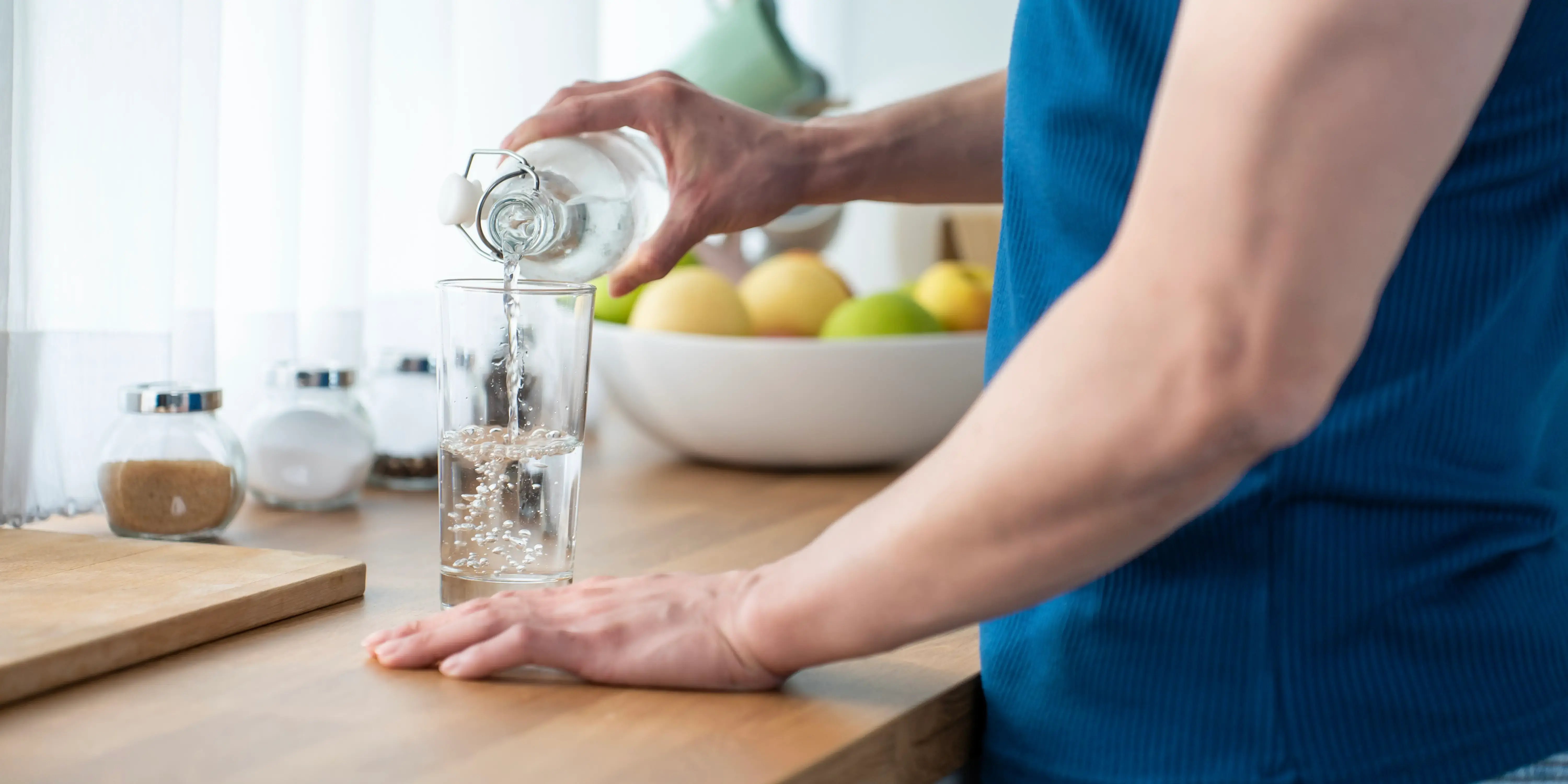 Hombre vertiendo agua limpia en vaso de vidrio para tener hábitos de vida saludable