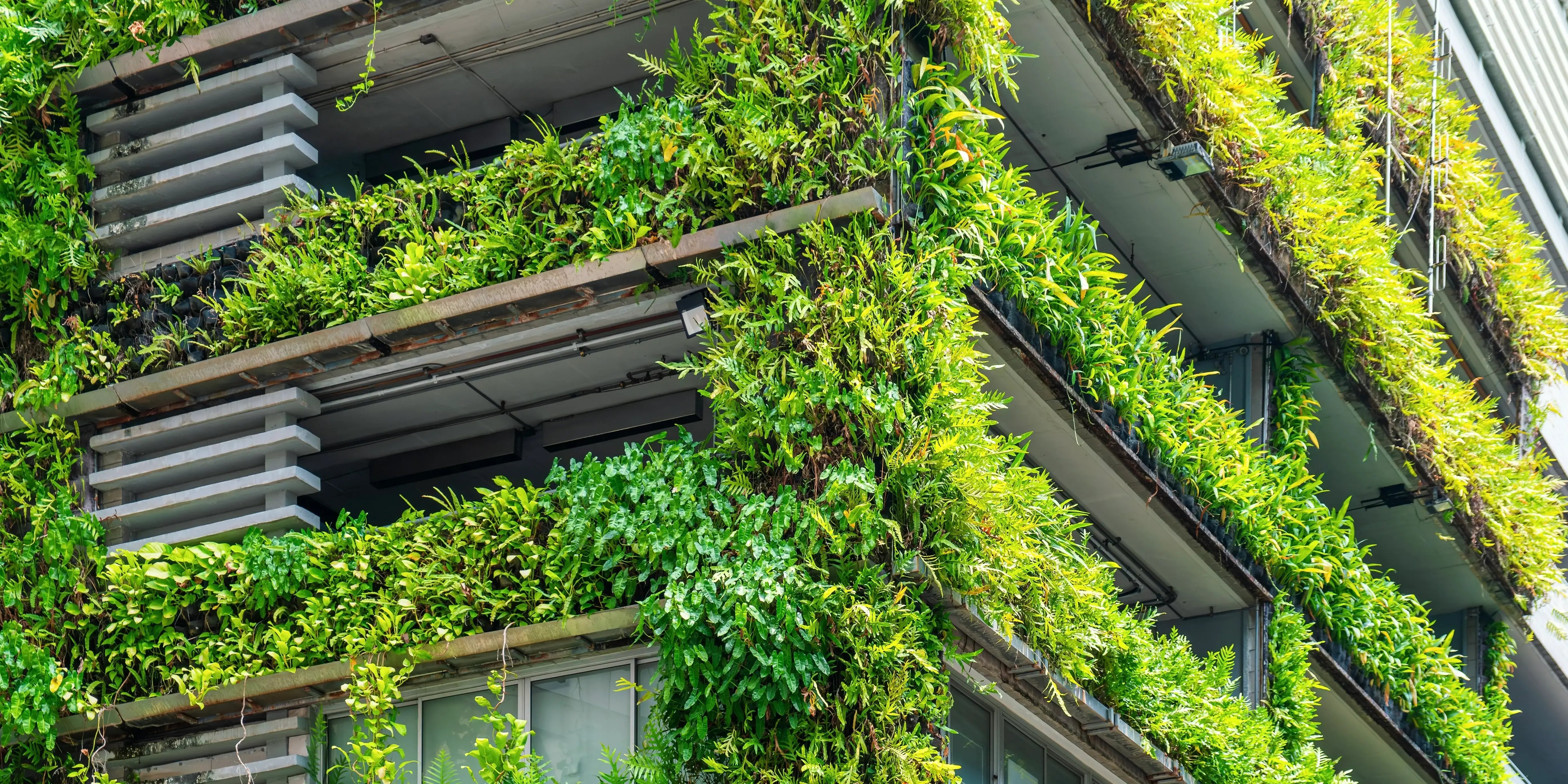 Moderna fachada de edificio con plantas verdes y jardines de Vertical
