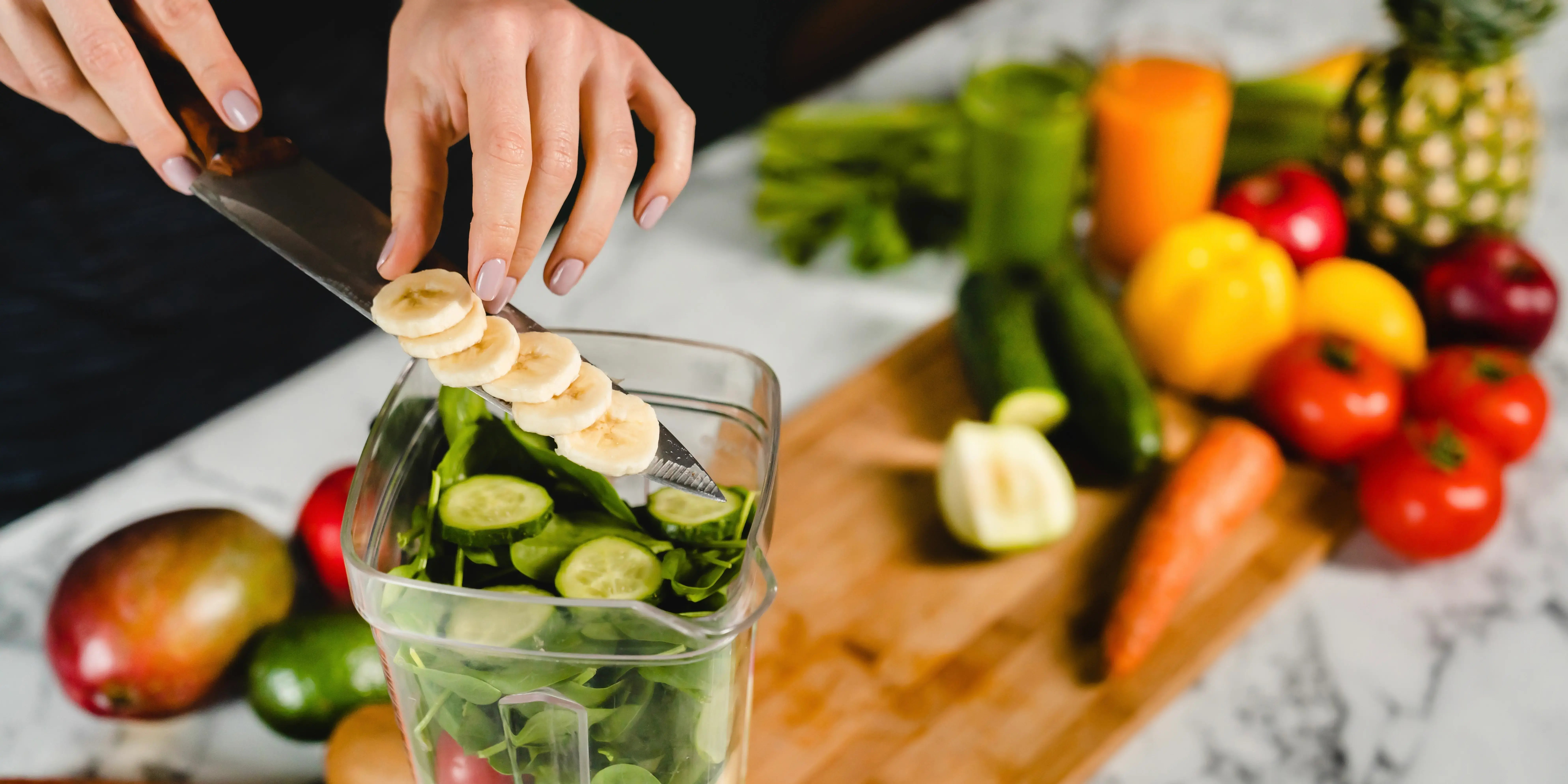 Mujer agregando plátano a la licuadora con cóctel verde de desintoxicación para tener hábitos de vida saludable