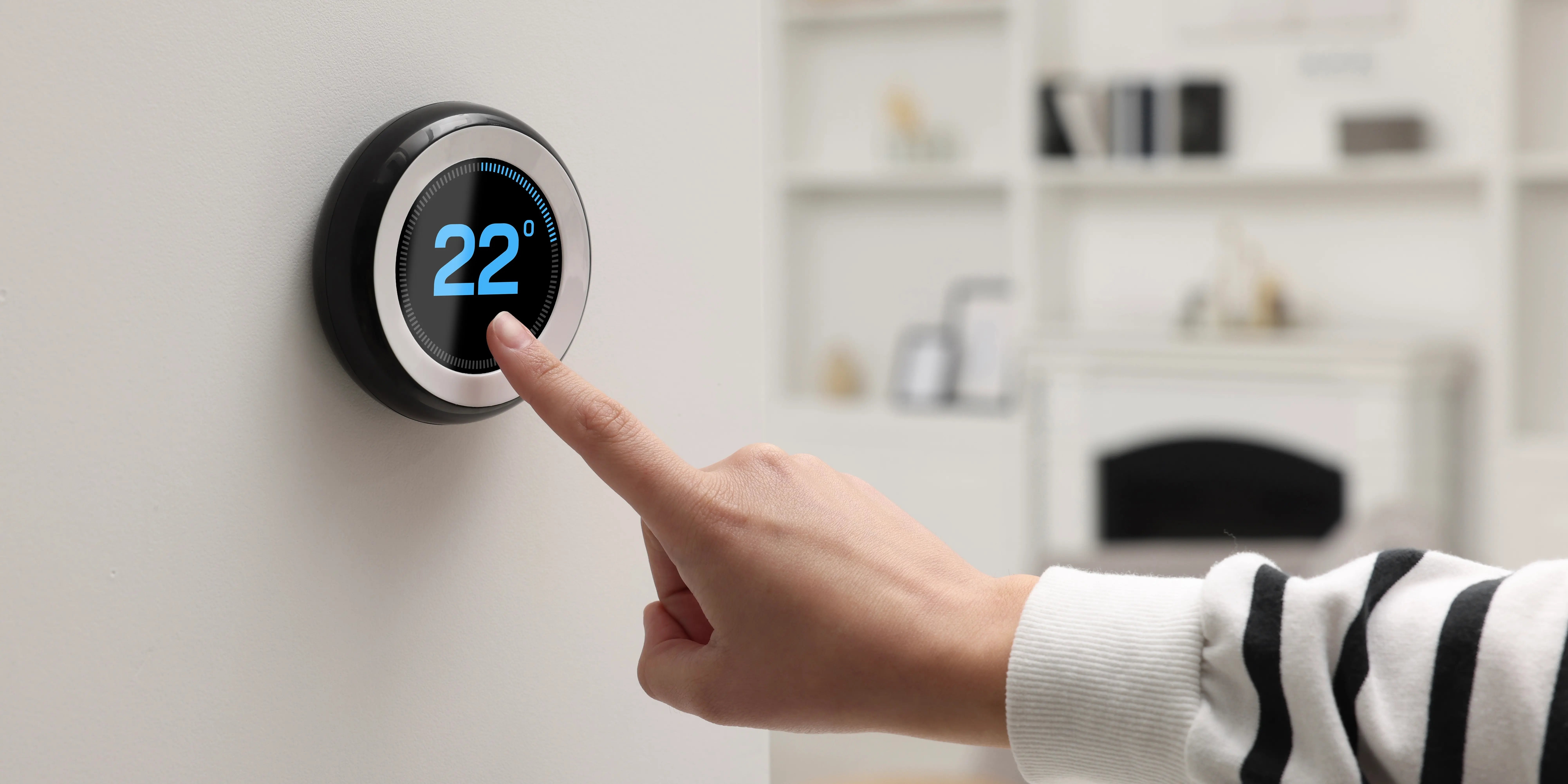 Mujer ajustando la temperatura de la casa con un termostato inteligente