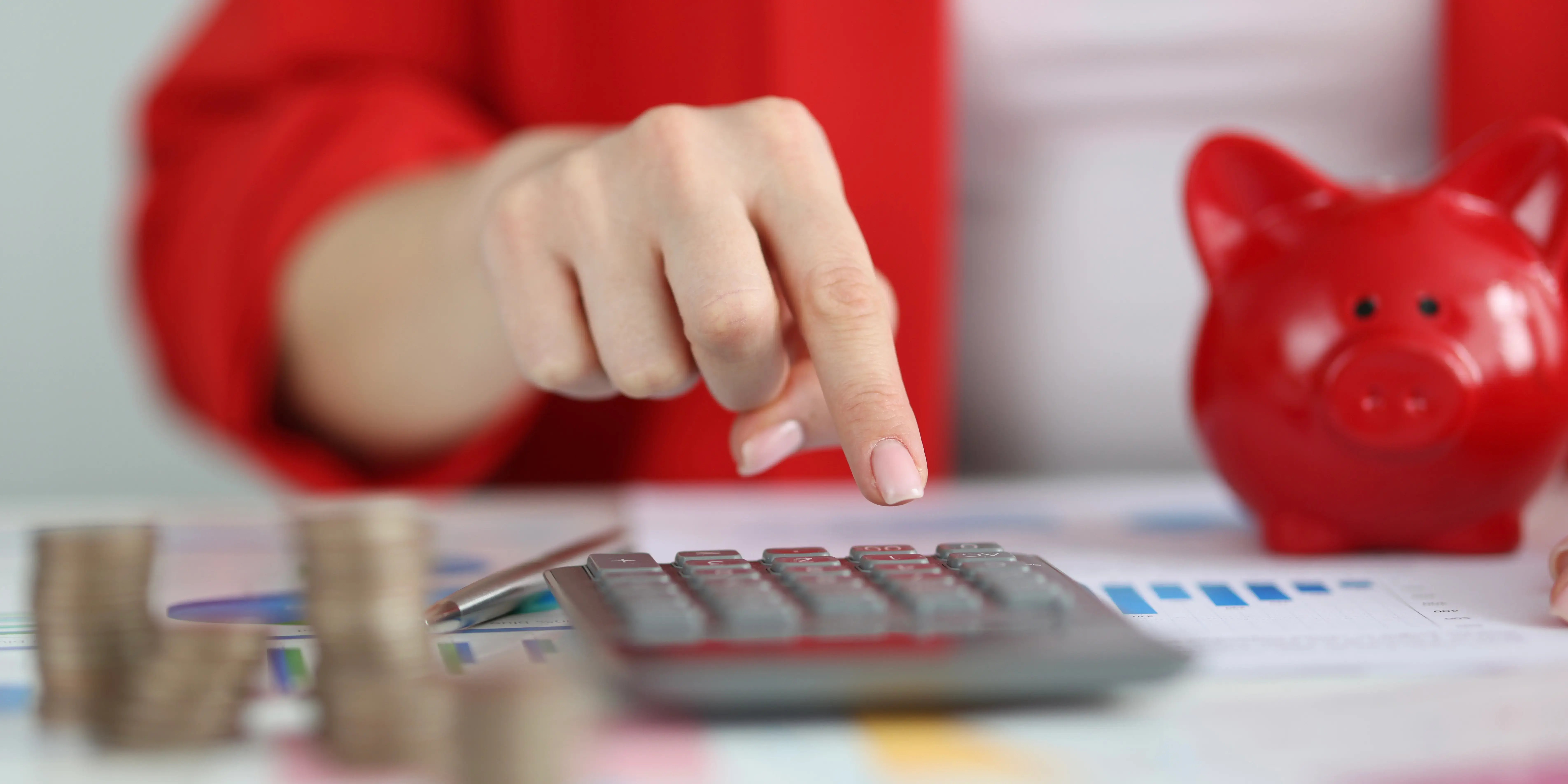 Mujer con una calculadora, torres de monedas y una alcancía impulsando el desarrollo económico con fondos de inversión