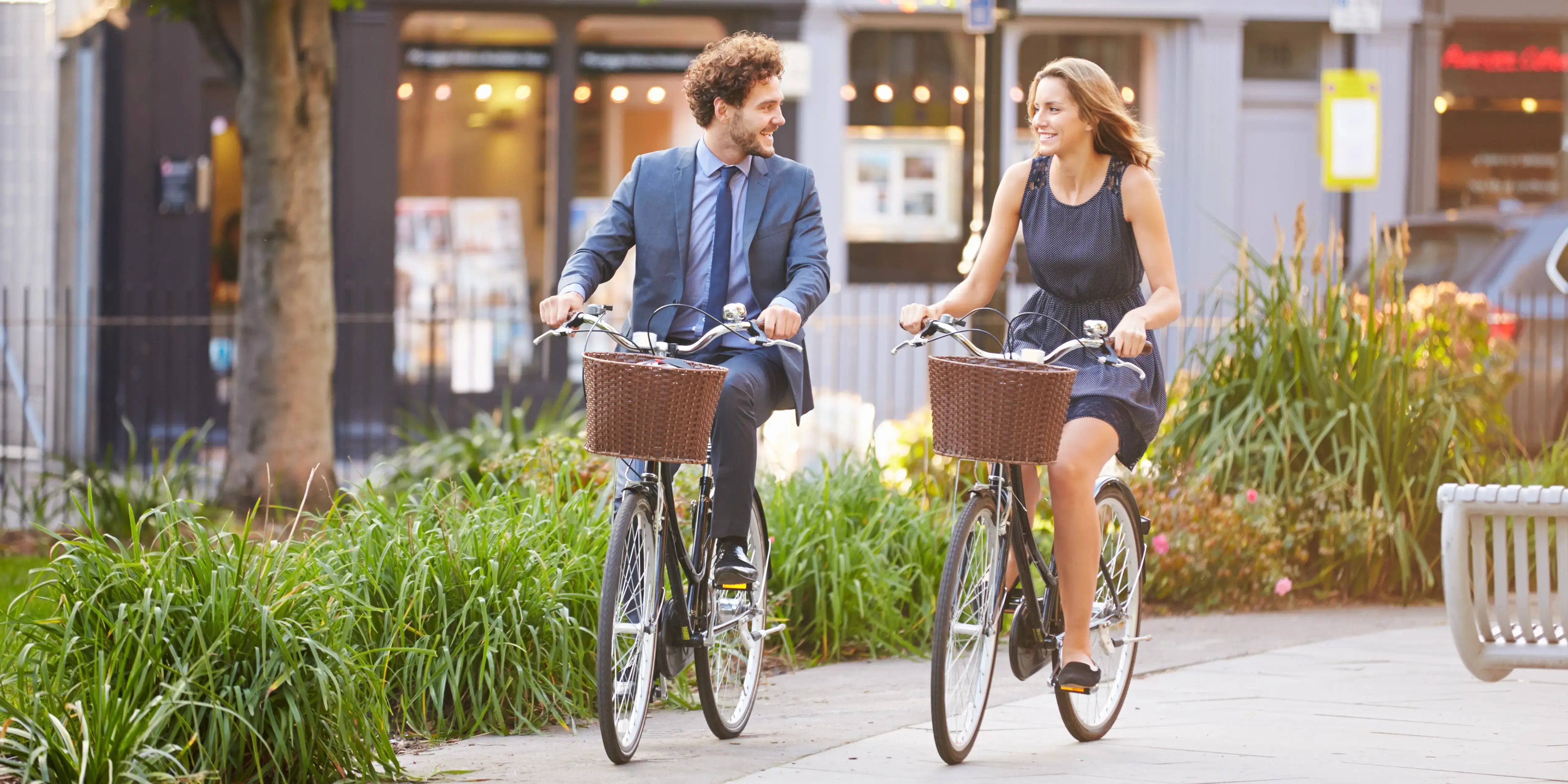 Mujer de negocios y hombre de negocios en bicicleta a través del parque en Bosque Real