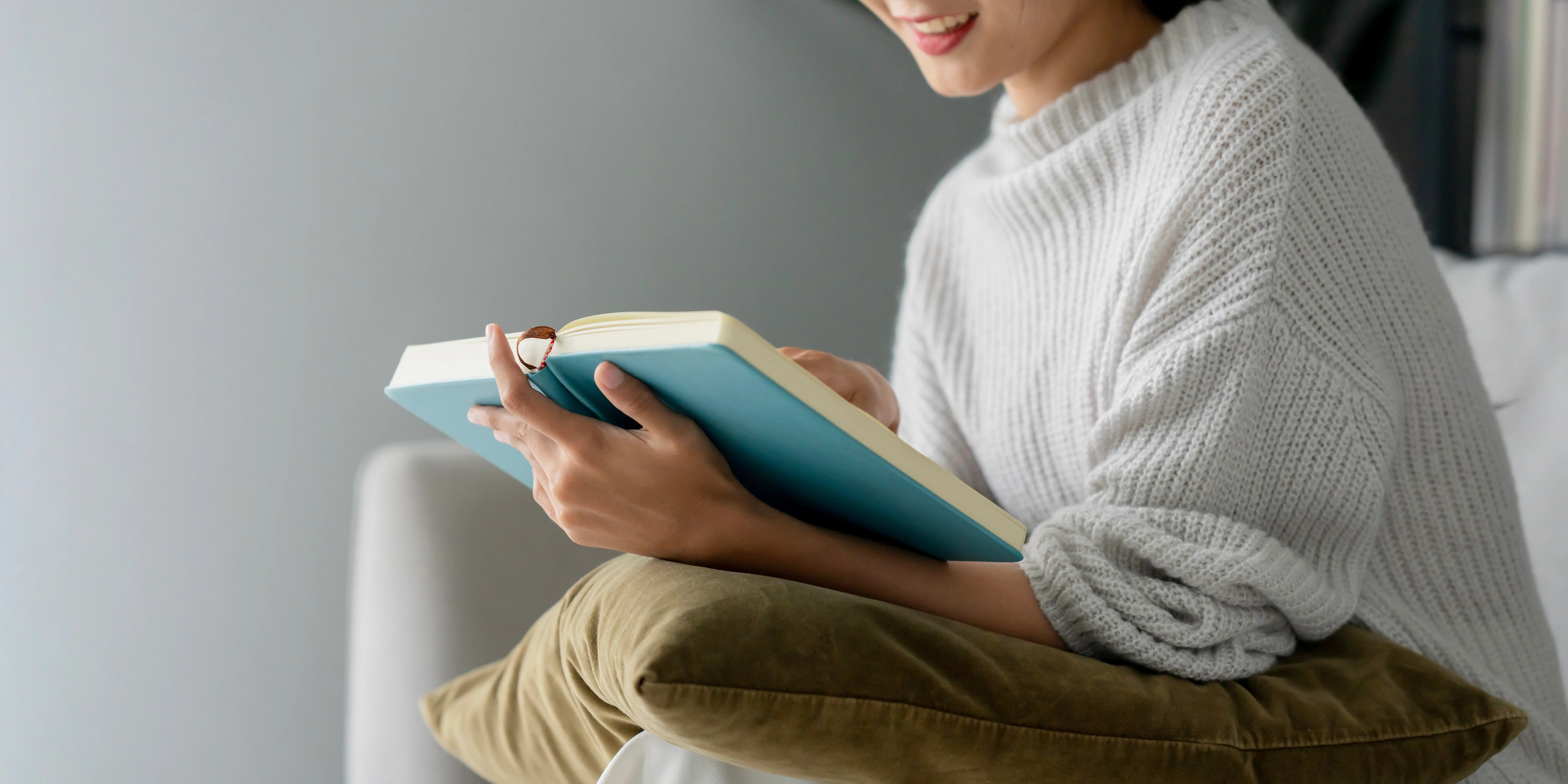 Mujer feliz en casa sosteniendo un libro y leyento para tener hábitos de vida saludable