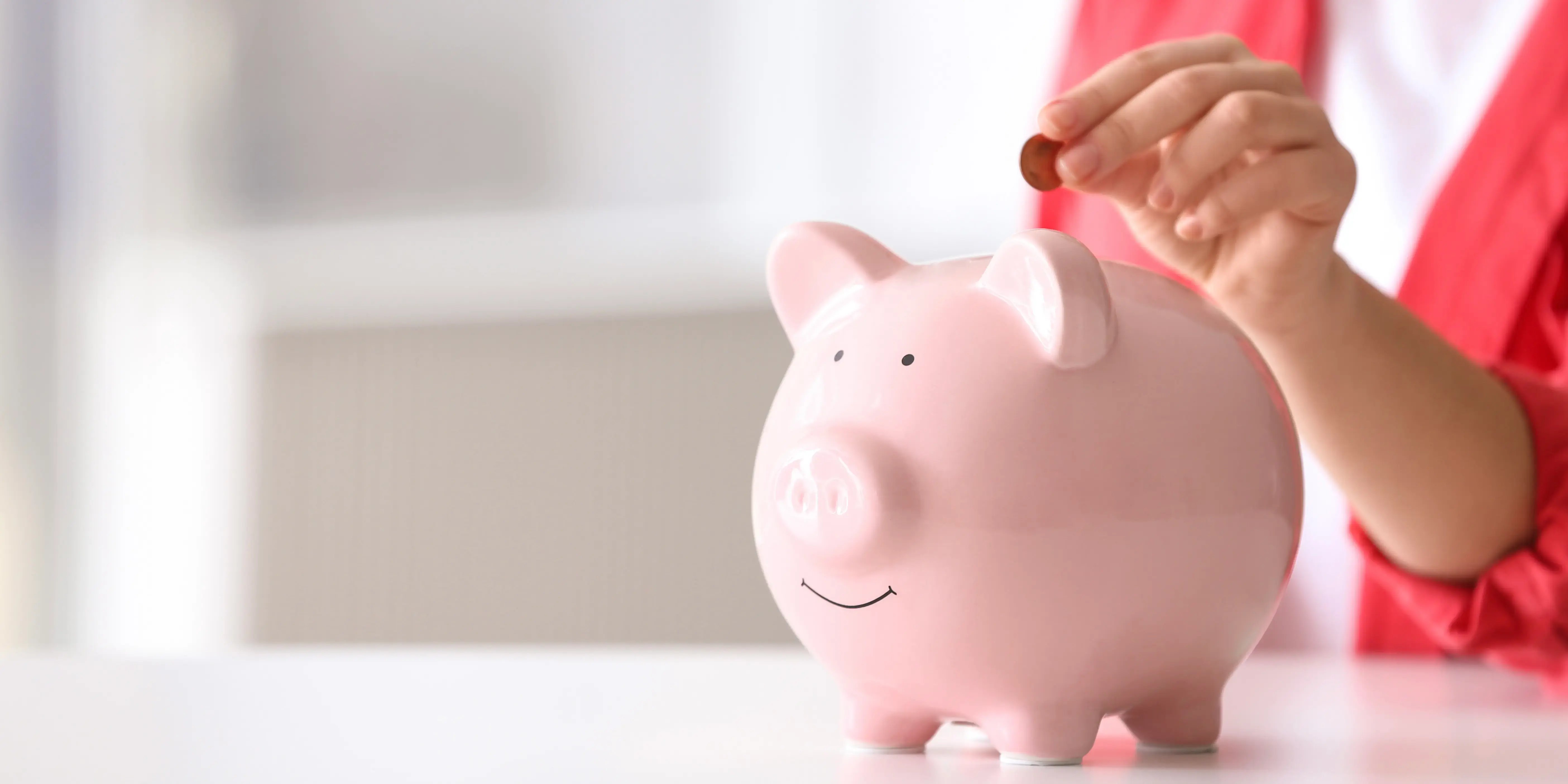 Mujer metiendo una moneda a una alcancía de cerdo para comenzar su plan personal de retiro