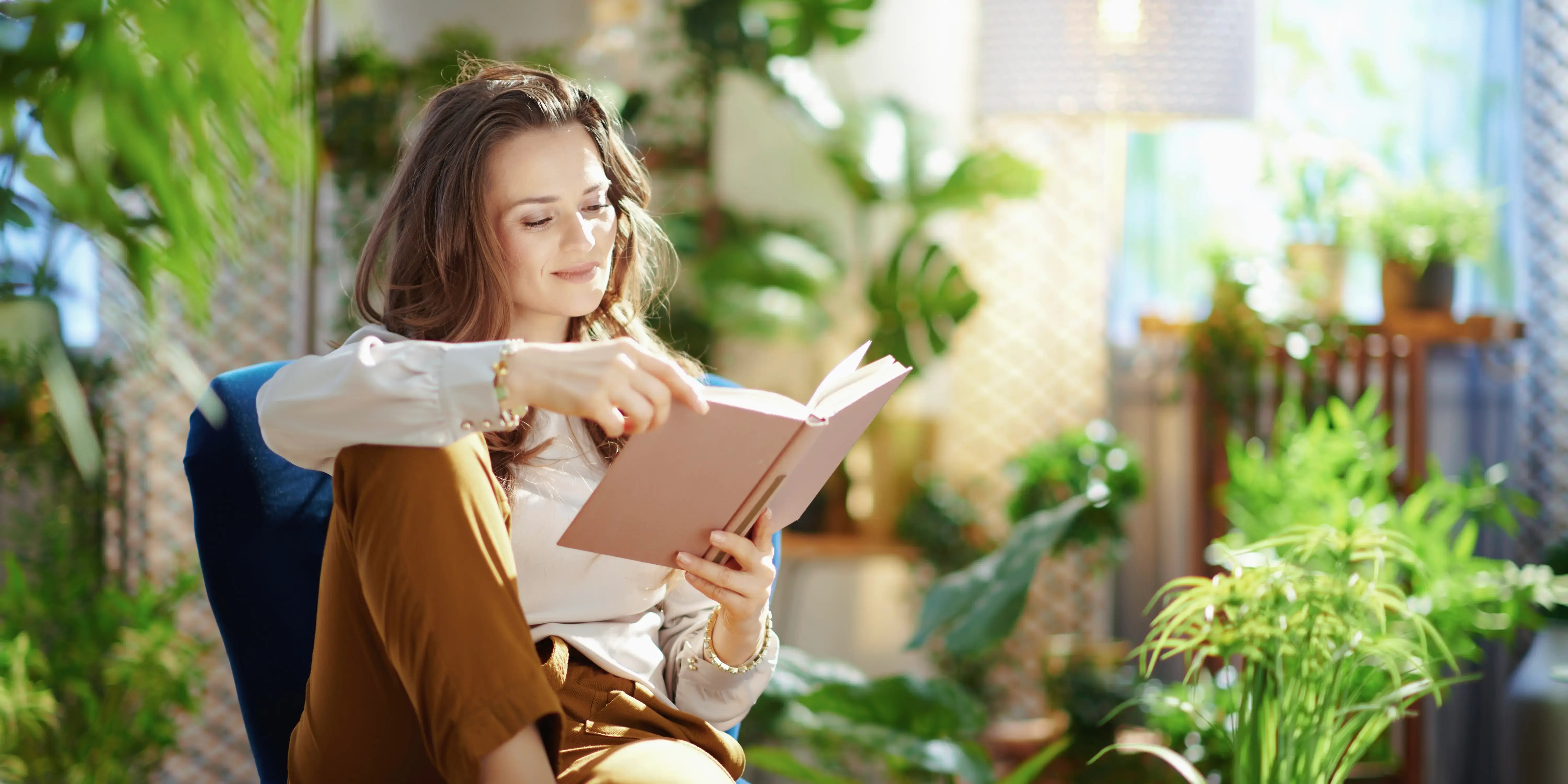 Mujer relajada sentada en la terraza de su casa que es un área tranquila y privada, además con una buena iluminación para crear entornos favorables a la salud