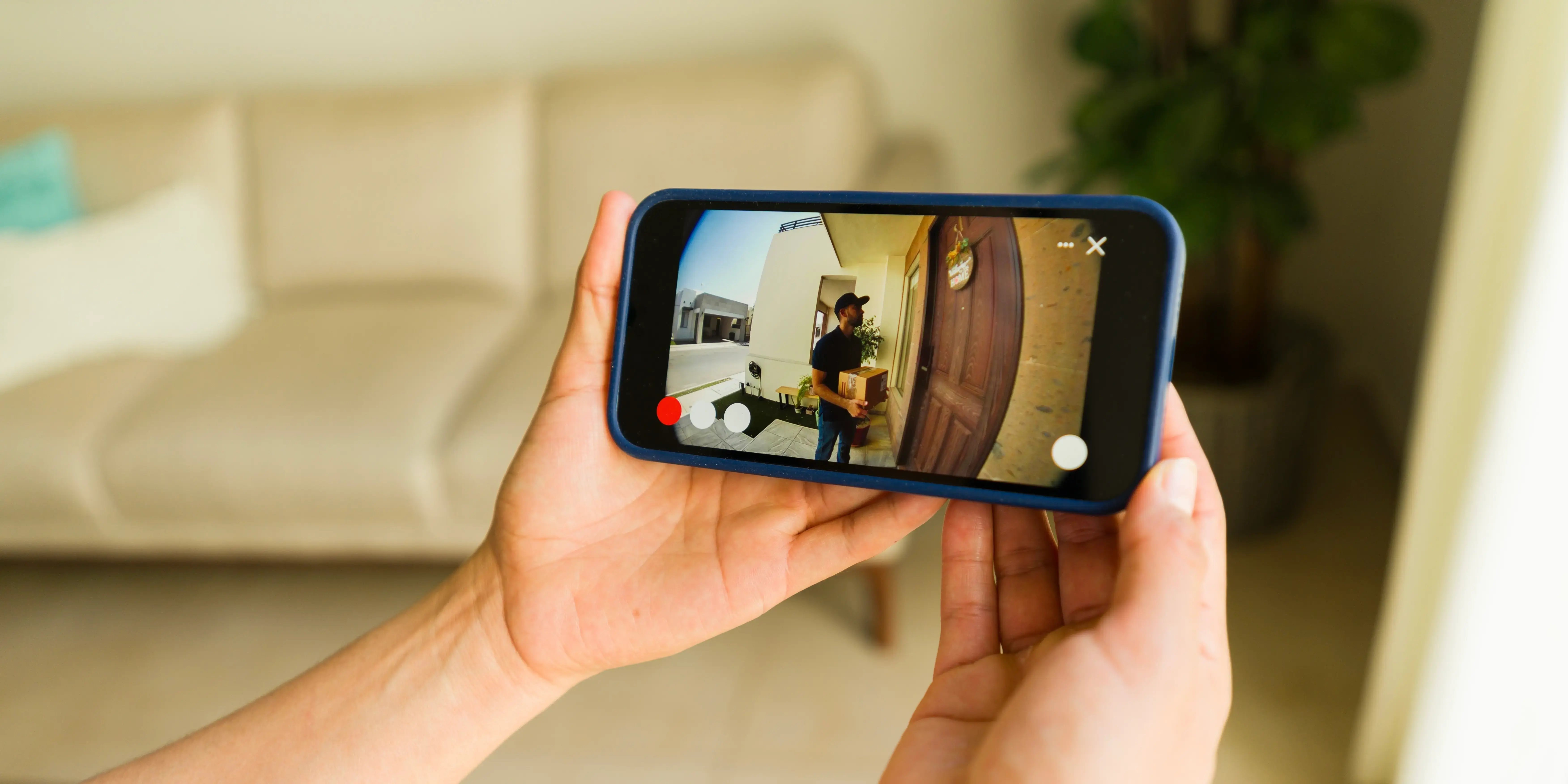 Mujer usando un App de timbre inteligente en un smartphone para ver a un repartidor dejando un paquete como idea de domótica en el hogar