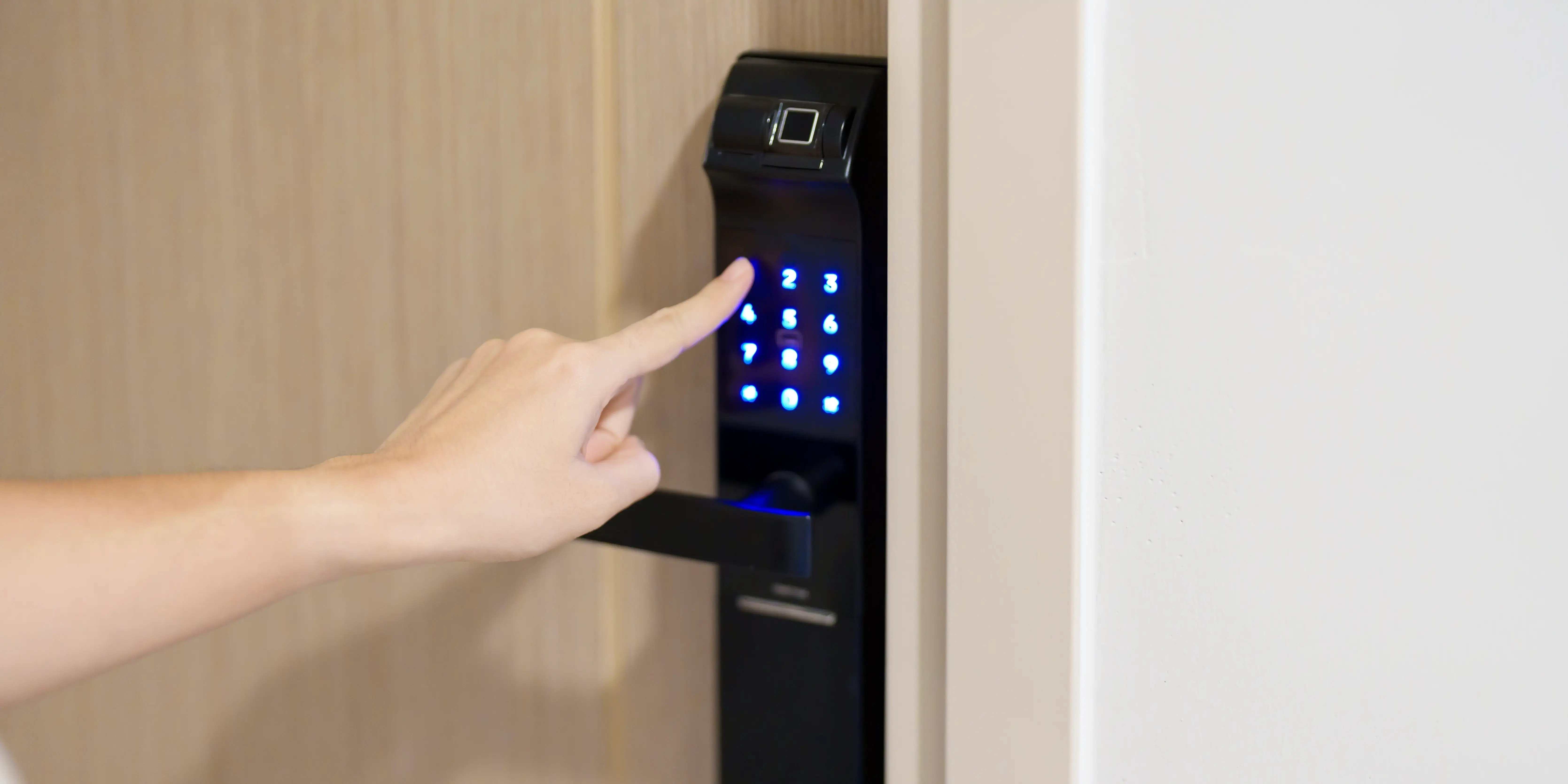 Persona presionando con la mano el número PIN para que la cerradura de la puerta digital de una casa inteligente se abra