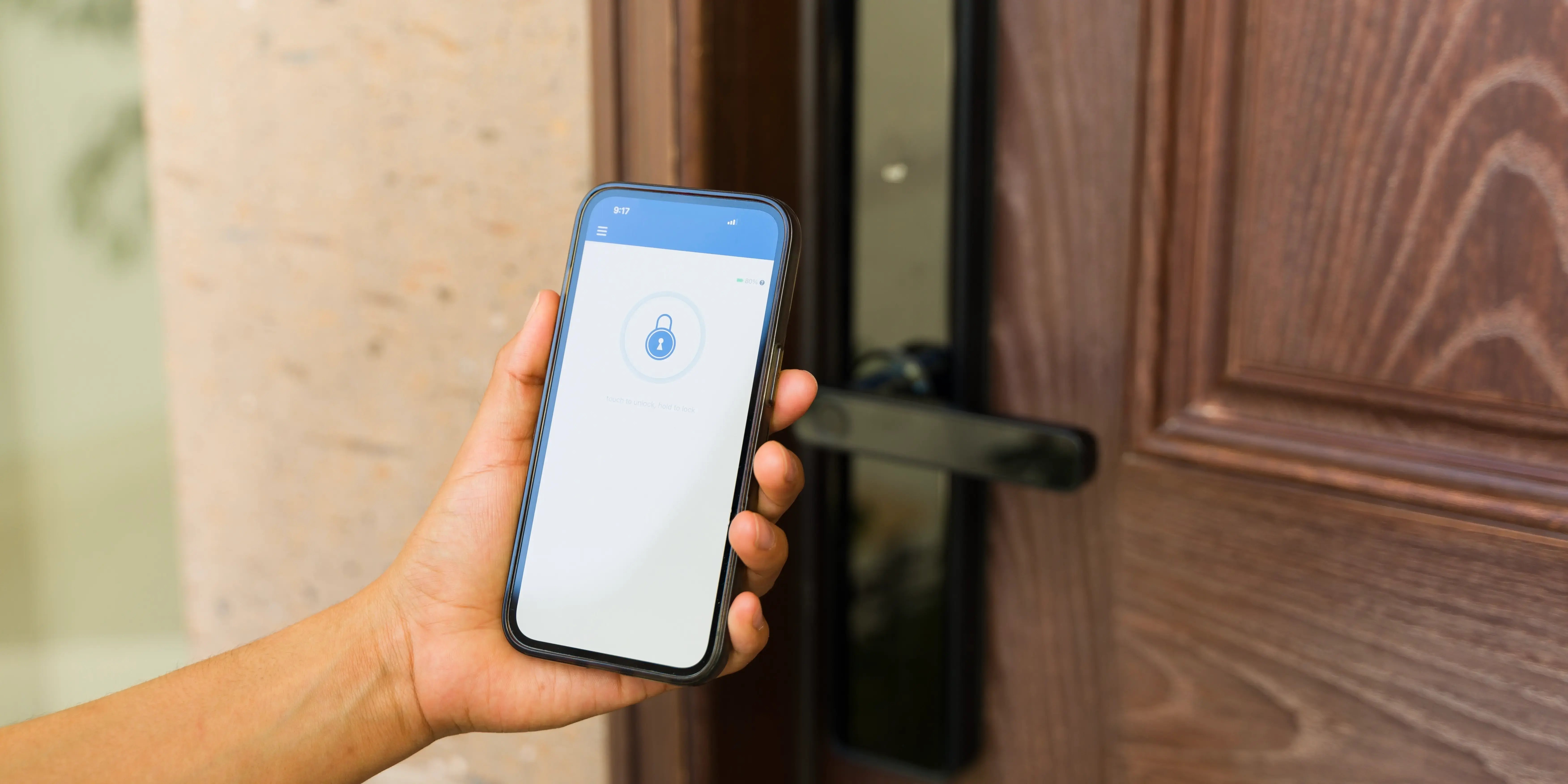 Persona sosteniendo un teléfono inteligente que desbloquea la puerta de un apartamento con una llave digital como idea de domótica en el hogar