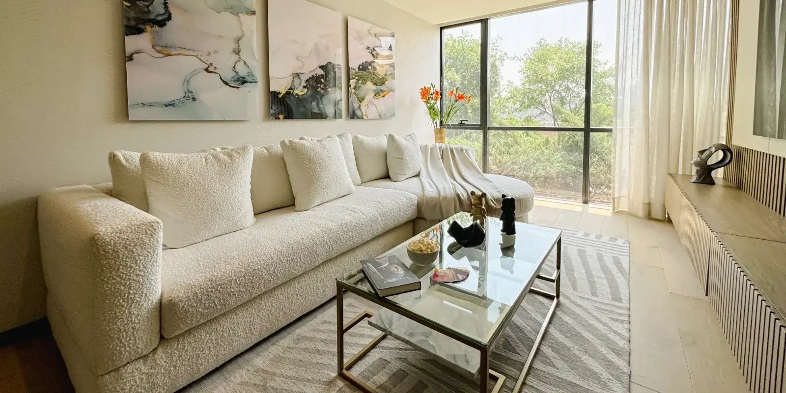 Sala con sillón blanco y ventanal del departamento Madison Bosque Real