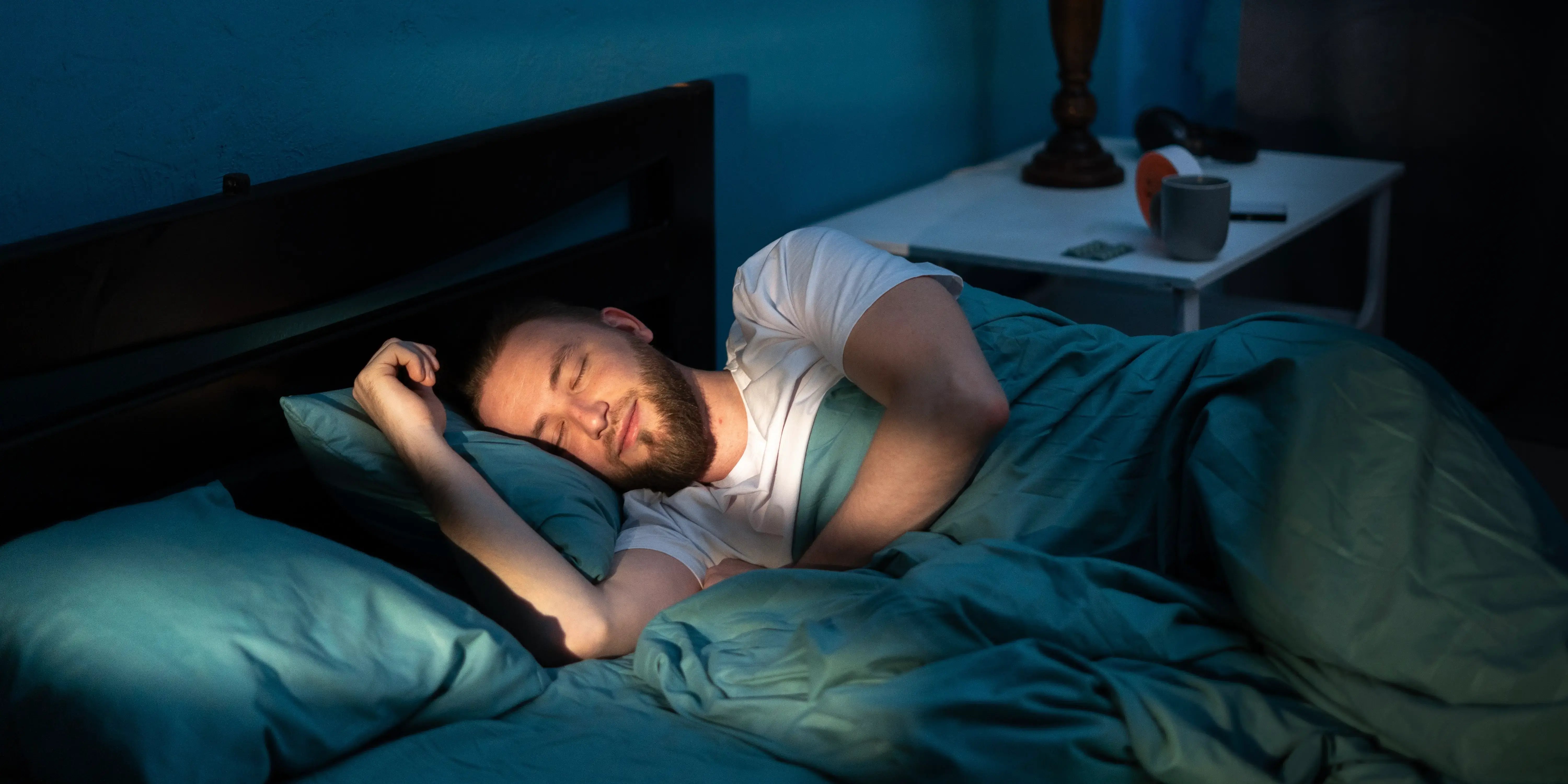 Un hombre durmiendo en una cama en su dormitorio por la noche para tener hábitos de vida saludable