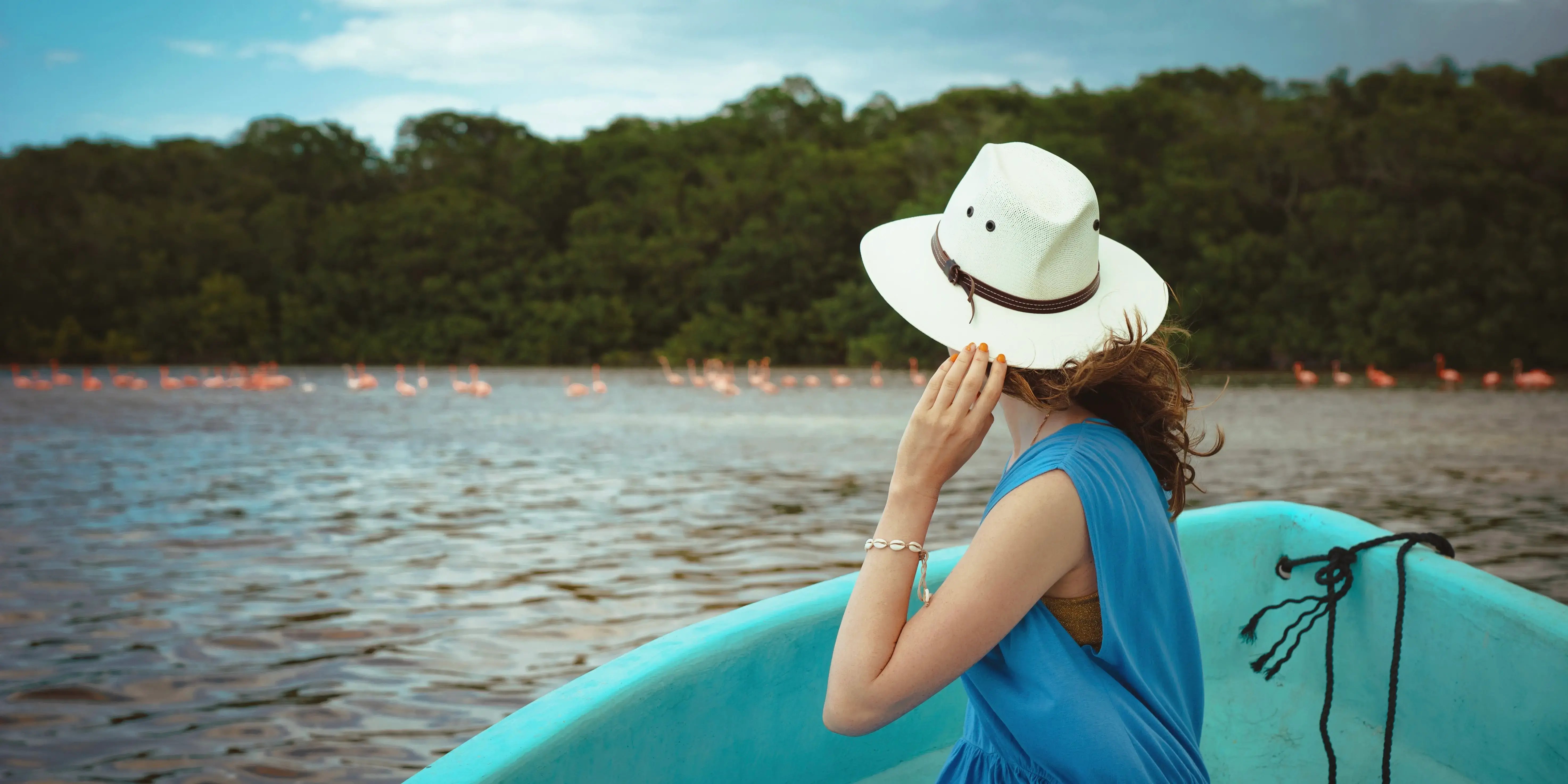 Una joven turista en un bote observa flamencos rosas en el Parque Nacional Celestun en México