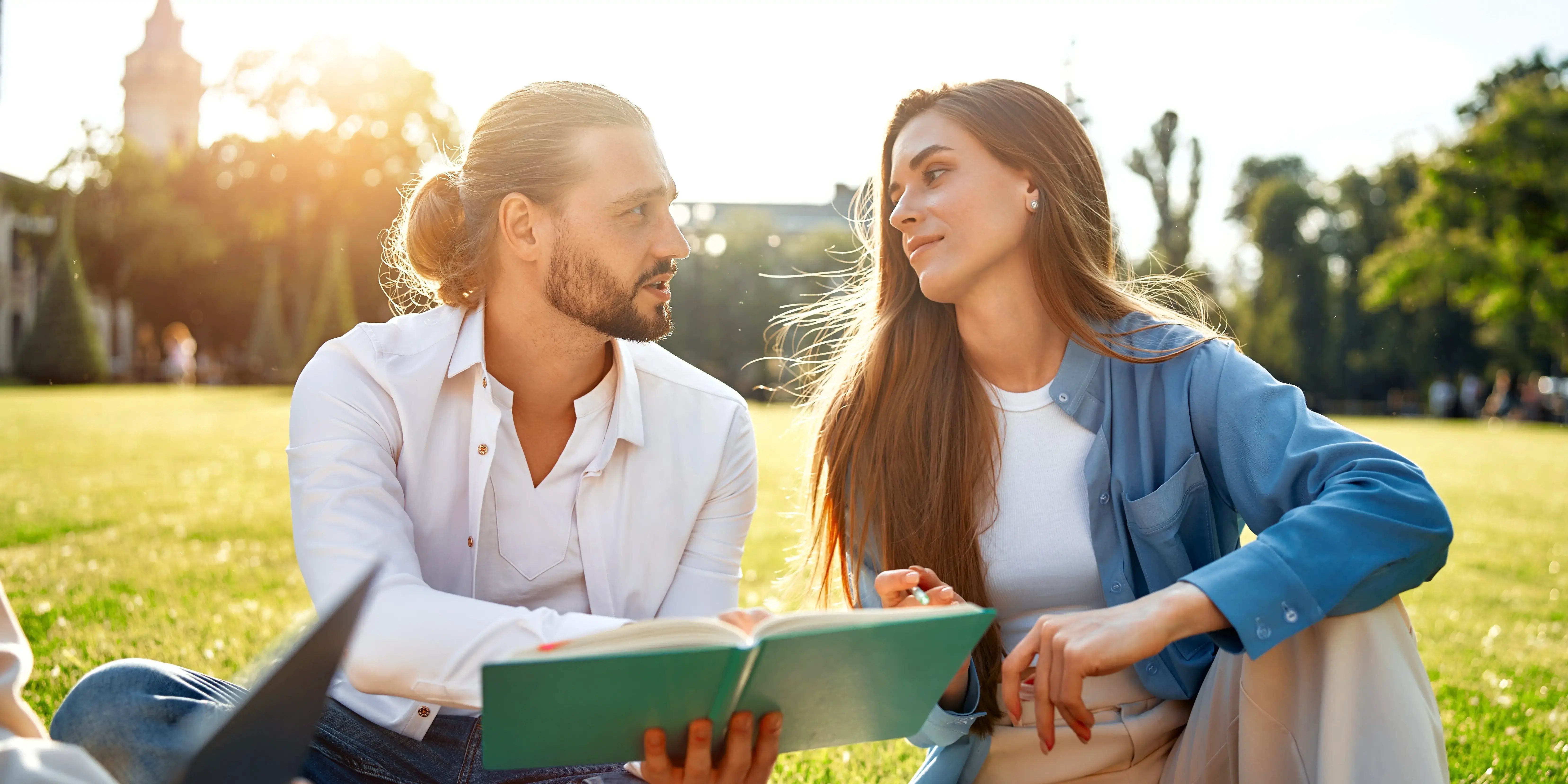 Una pareja joven disfruta de un tiempo agradable y tranquilo en el parque, intercambiando ideas de libros en un día soleado y viviendo el lujo con estrategia