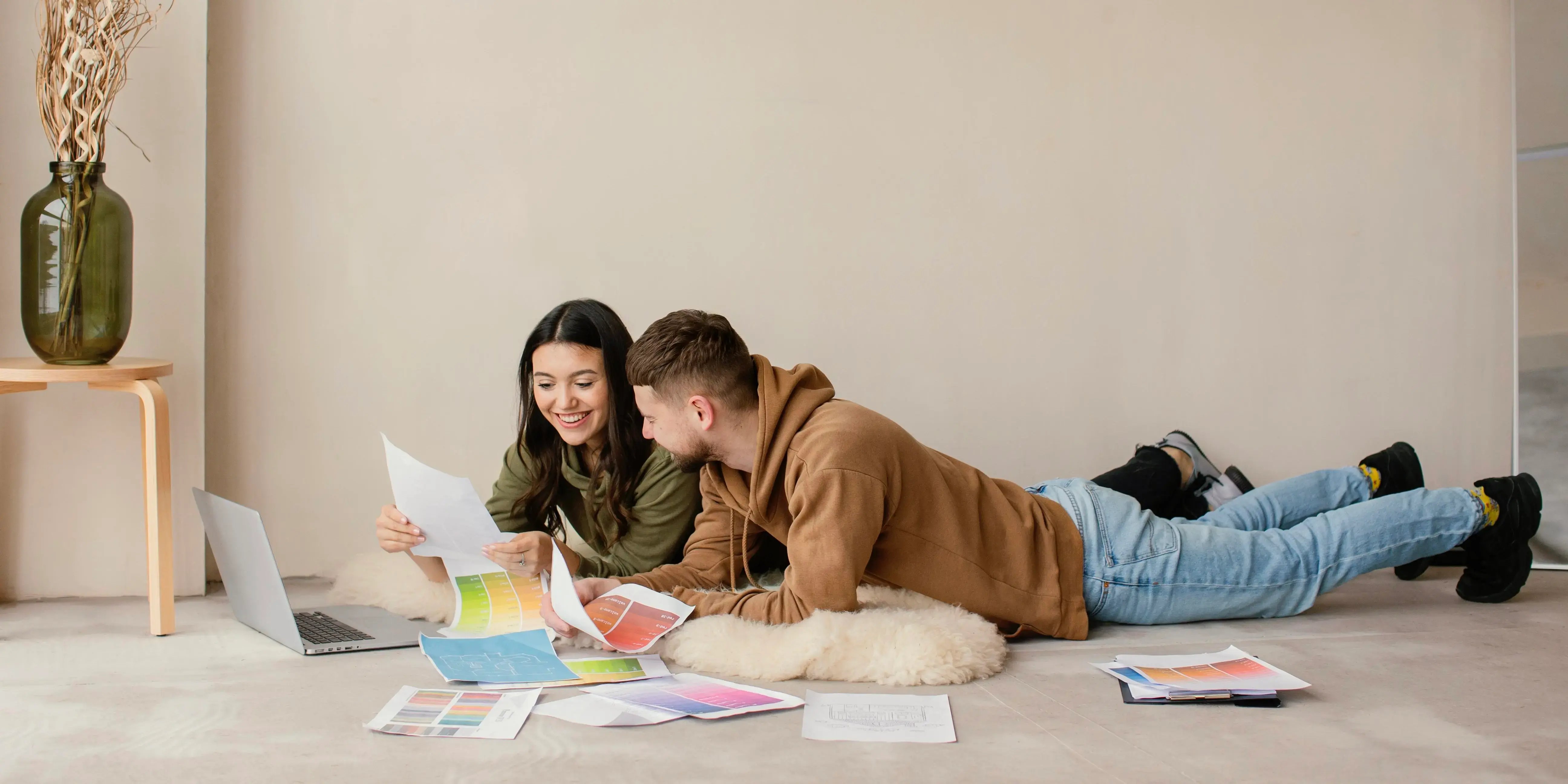 Pareja tirada en el suelo eligiendo colores para pintar paredes. Cómo el interiorismo puede mejorar la calidad de vida