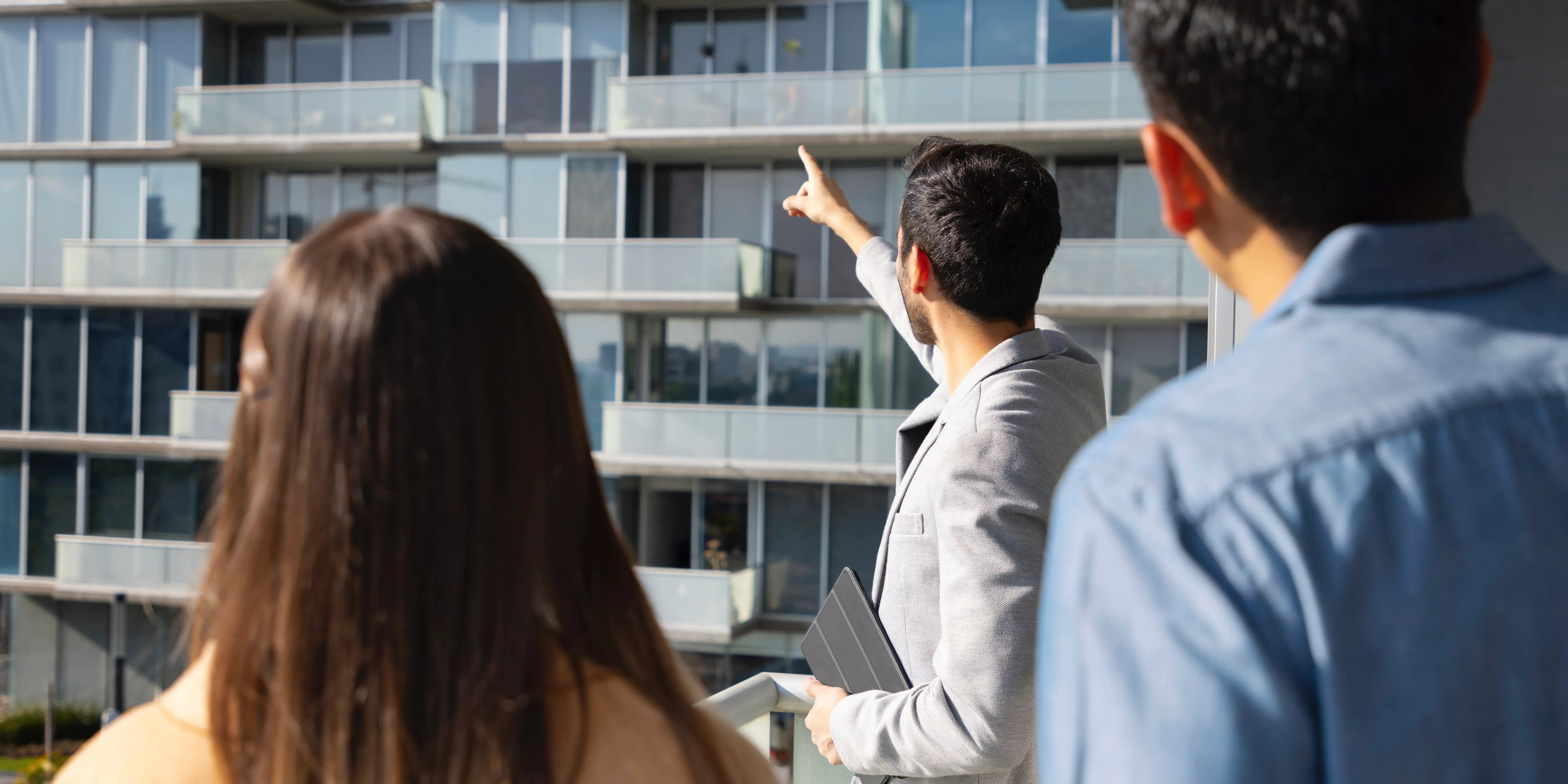 Bróker enseñando edificio. Comprar departamento, buena inversión