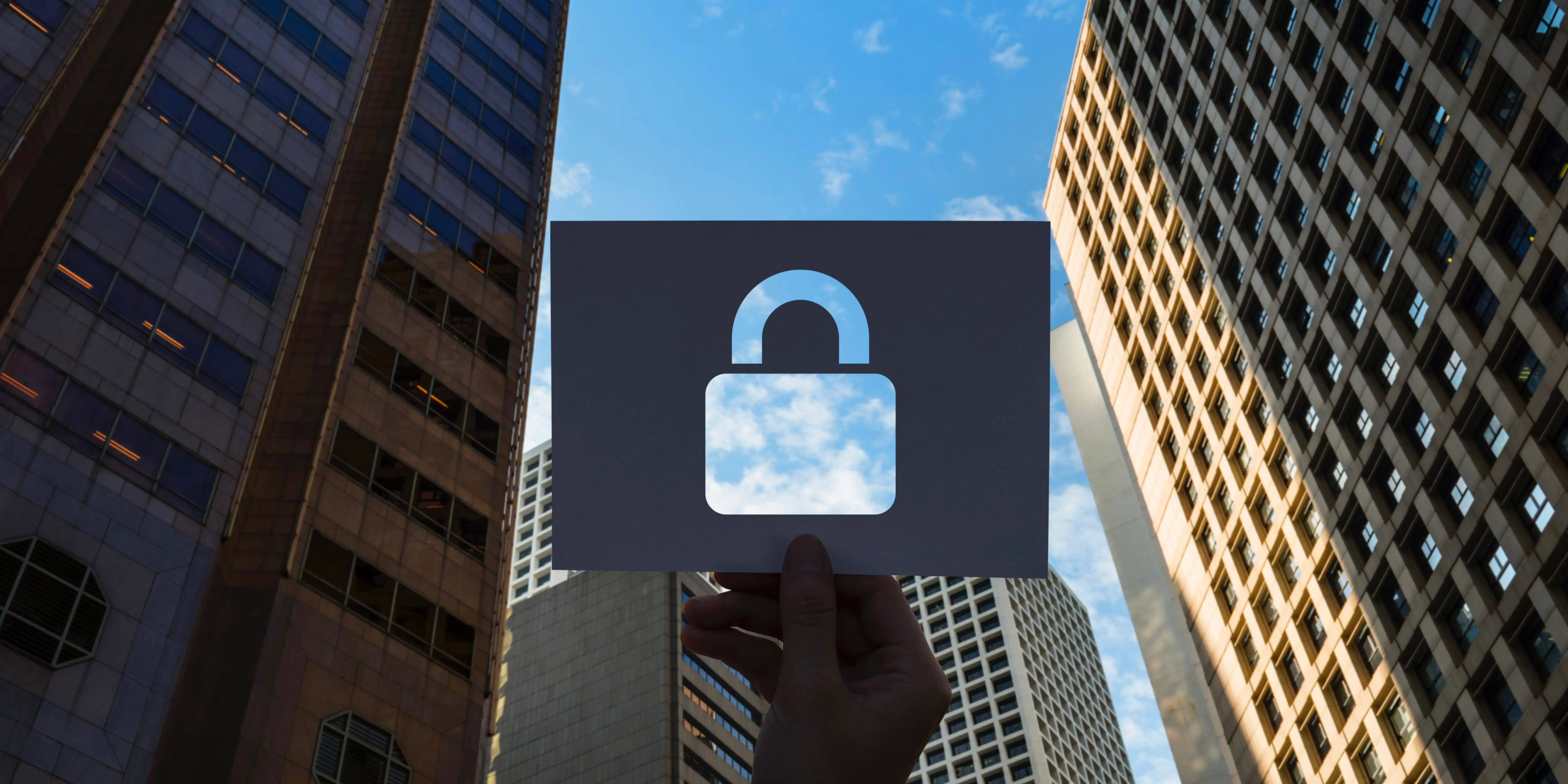 Mano sosteniendo un candado entre edificios. Privacidad en el hogar