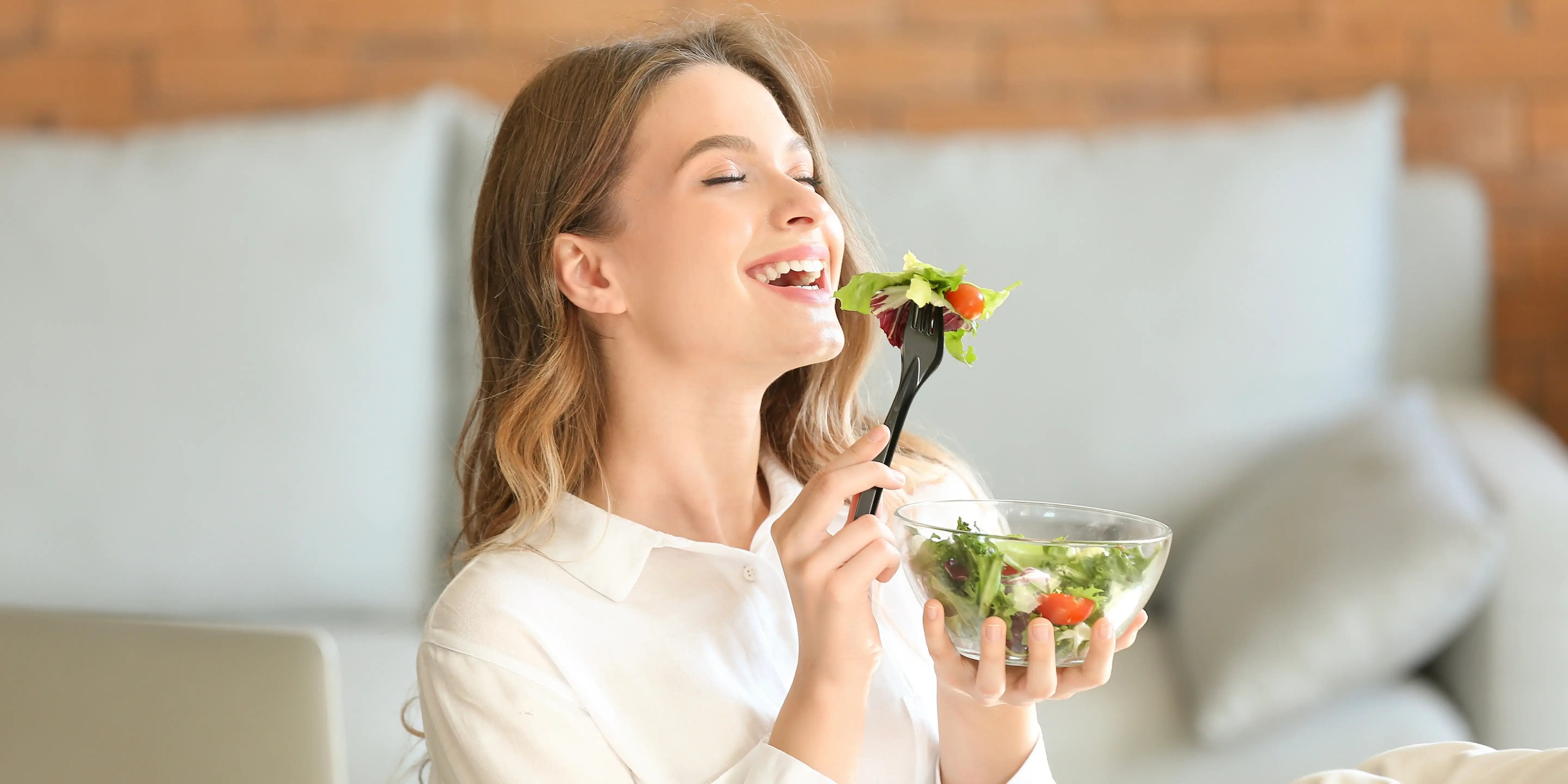 mujer feliz comiendo una ensalada. qué es el bienestar