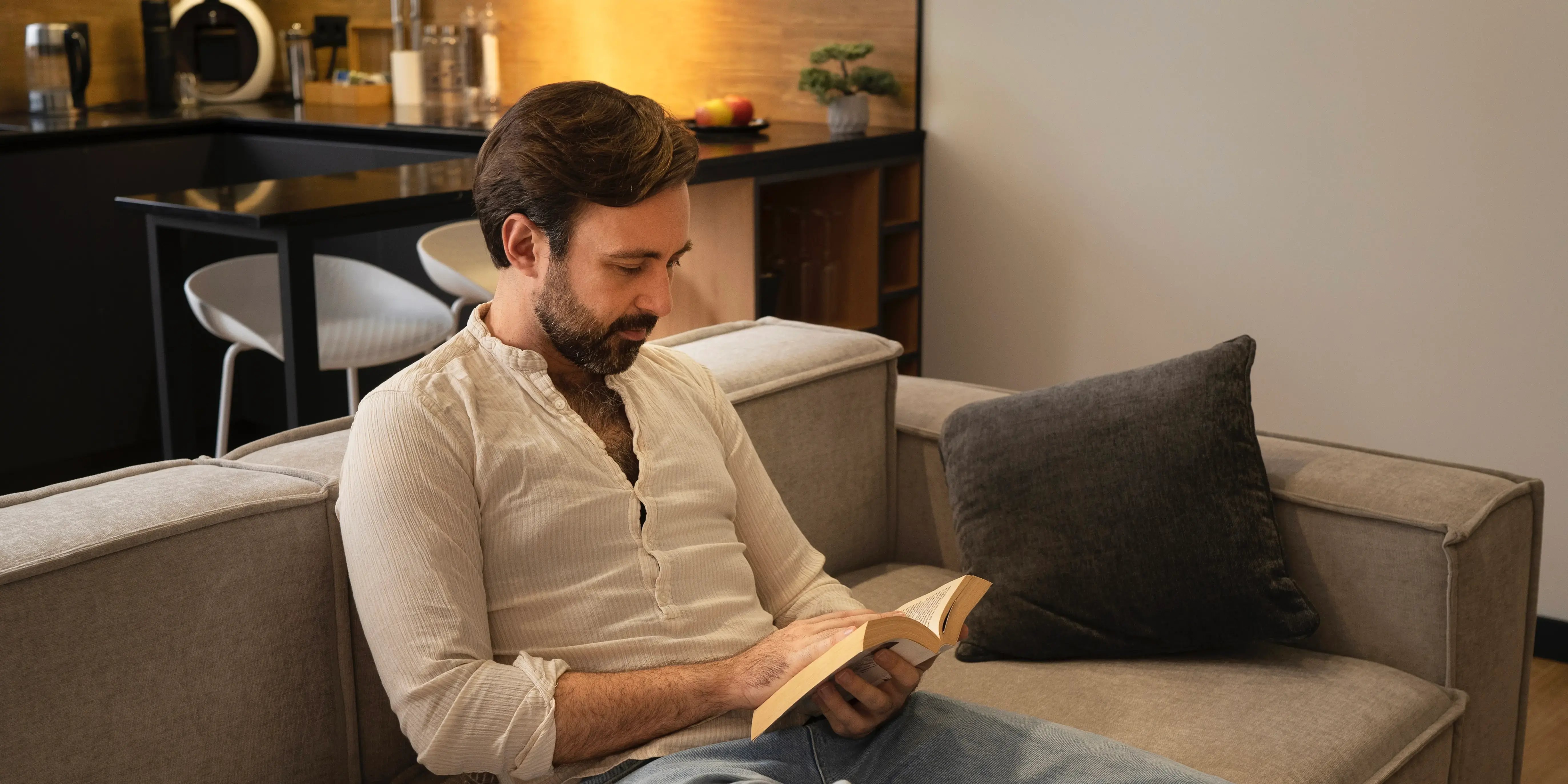 Hombre en la sala leyendo un libro. Relajación después de un día estresante