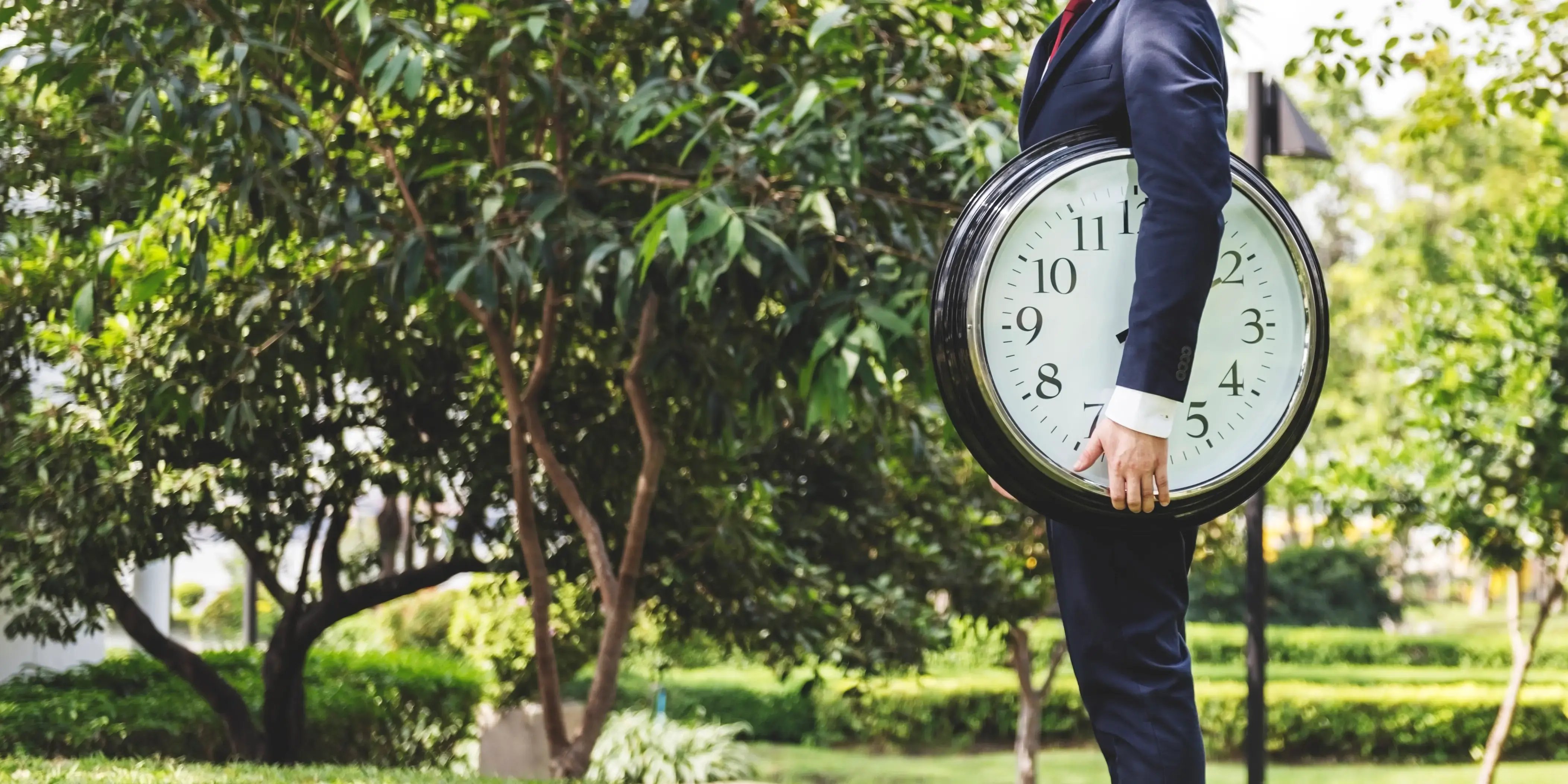 Hombre en el parque sosteniendo un reloj. El tiempo es el nuevo lujo